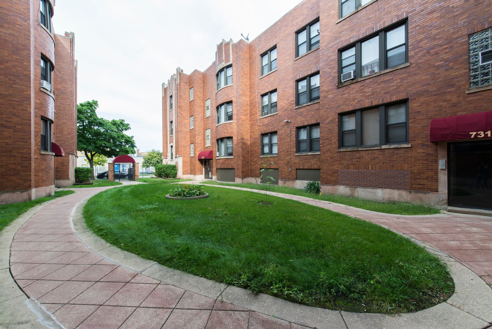 Brick apartment buildings with grass median and paved walkways.
