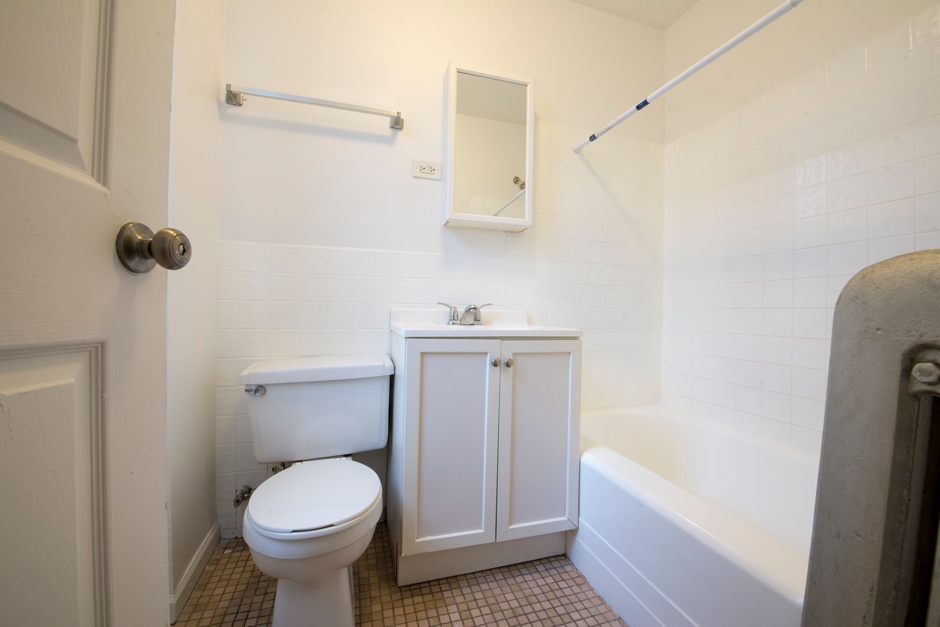 Small white bathroom with a toilet, sink, tub, and medicine cabinet.