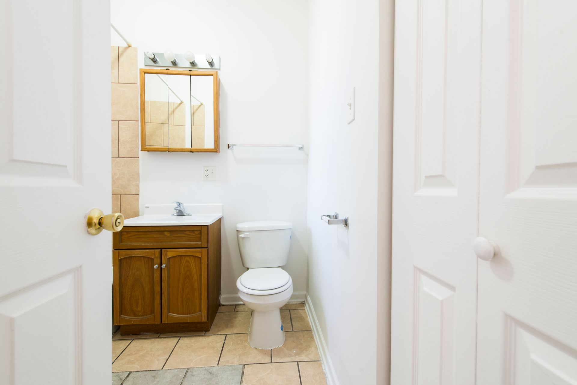 Bathroom interior with a toilet, vanity, and closed doors.