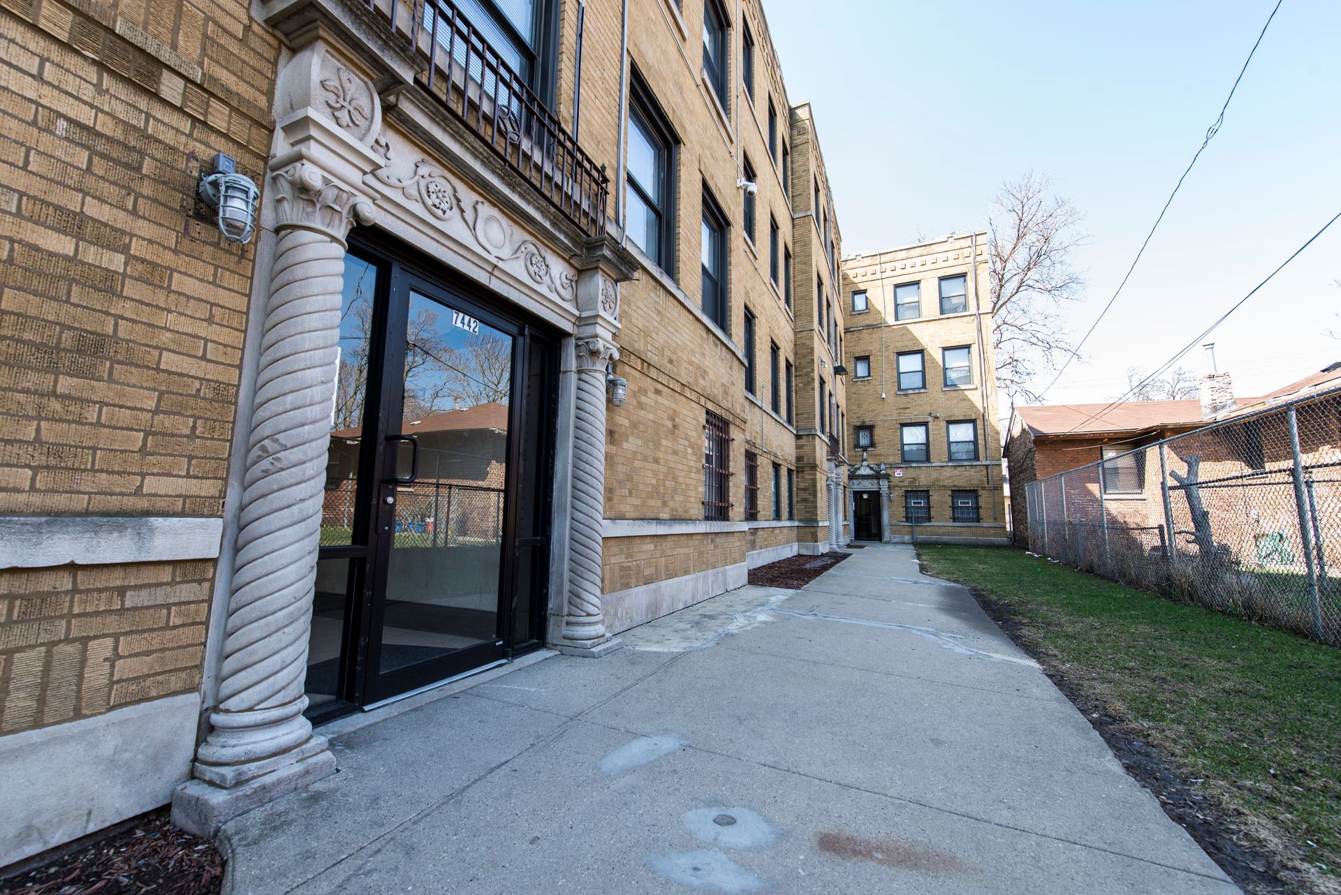 Exterior view of a brick apartment building with a pathway leading to a door.