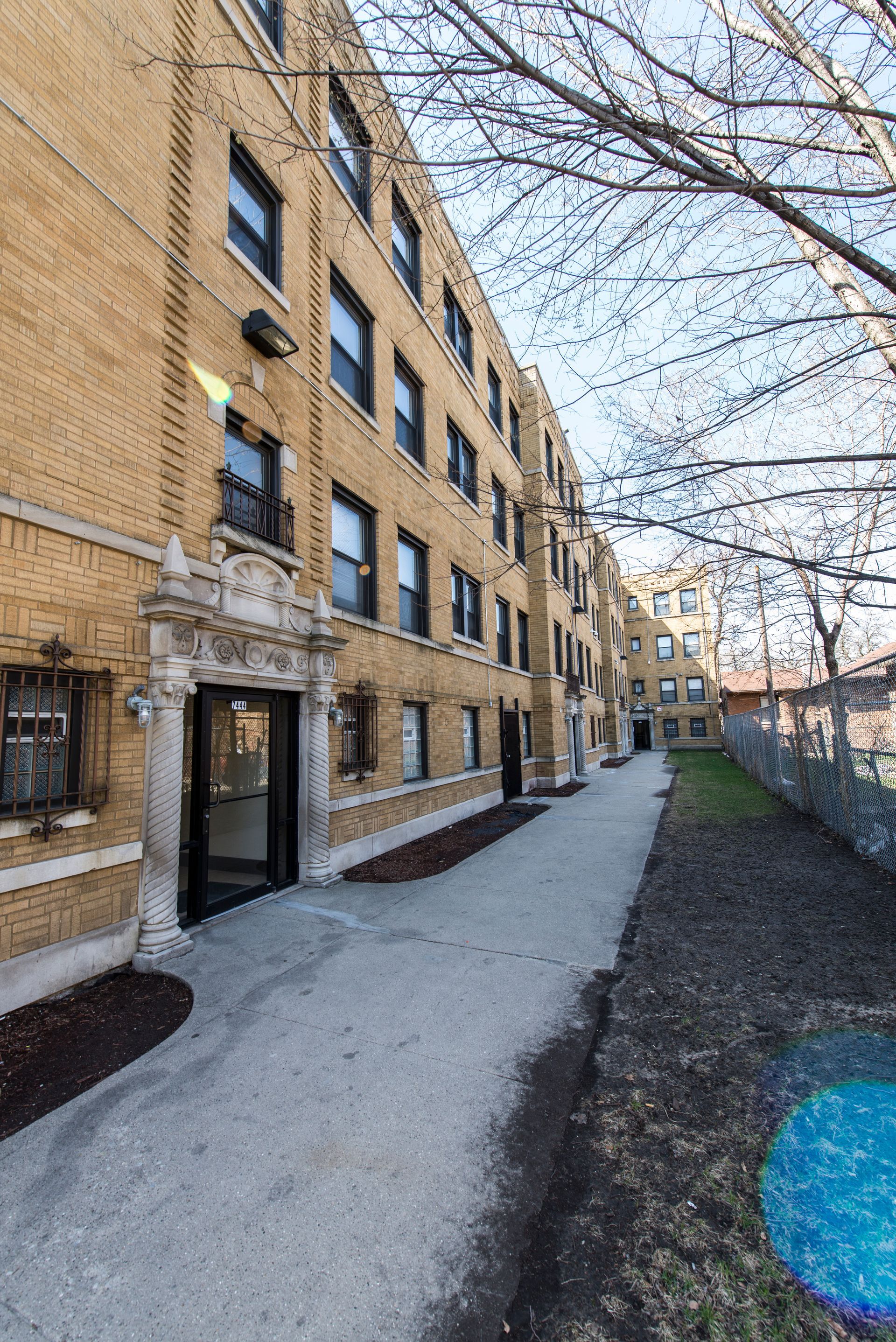 Yellow brick apartment building with walkway and a clear sky.