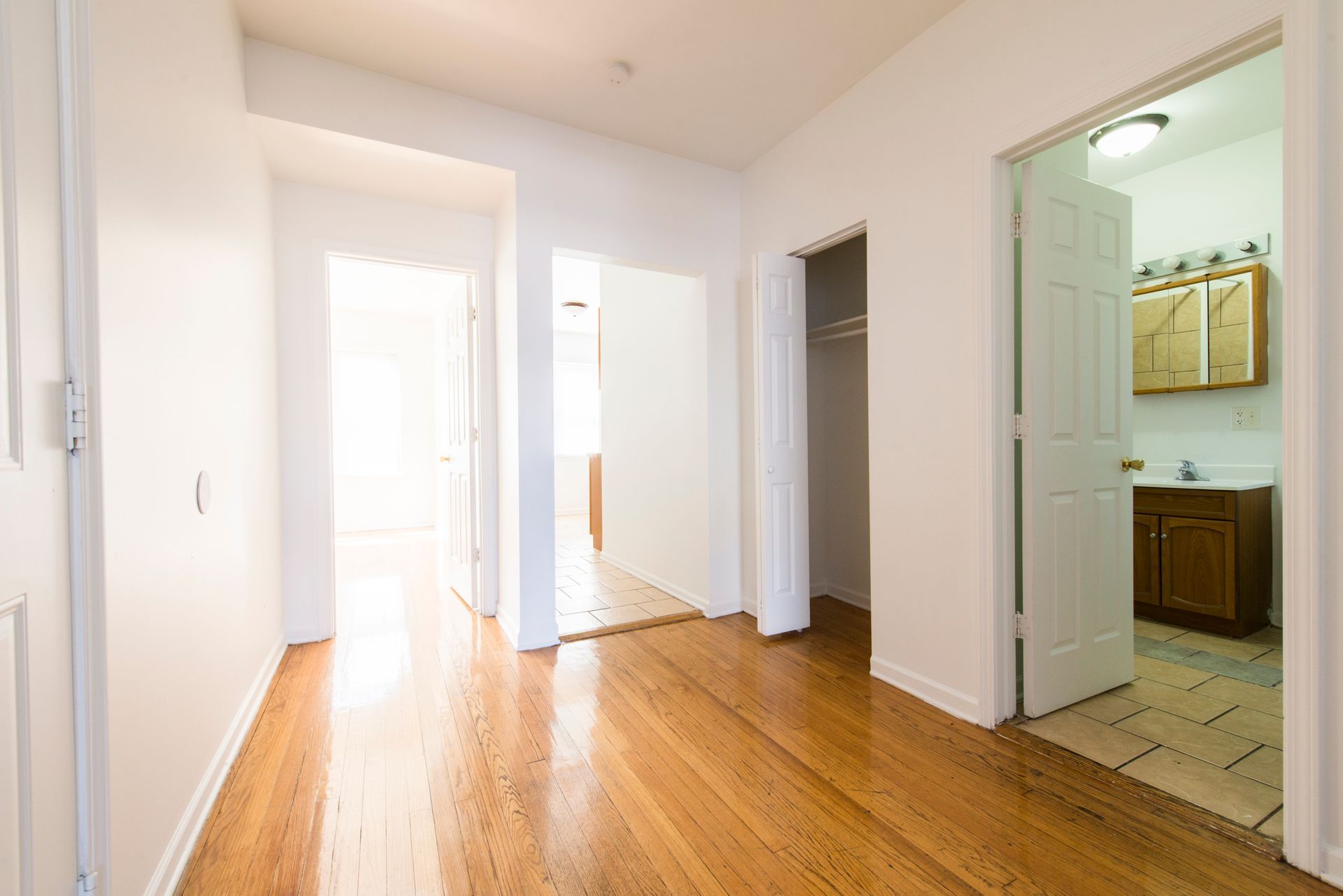 Hallway with wood floors, doorways, and bright natural light.