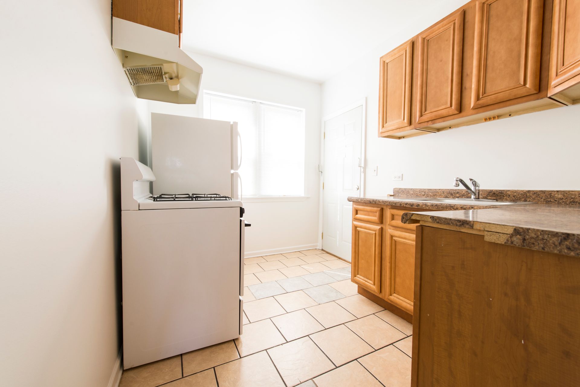 Small kitchen with white appliances, light wood cabinets, and tile floor.