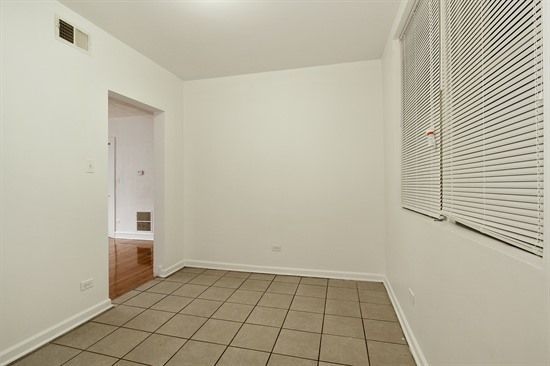 Empty room with tiled floor, white walls, and a window with blinds.