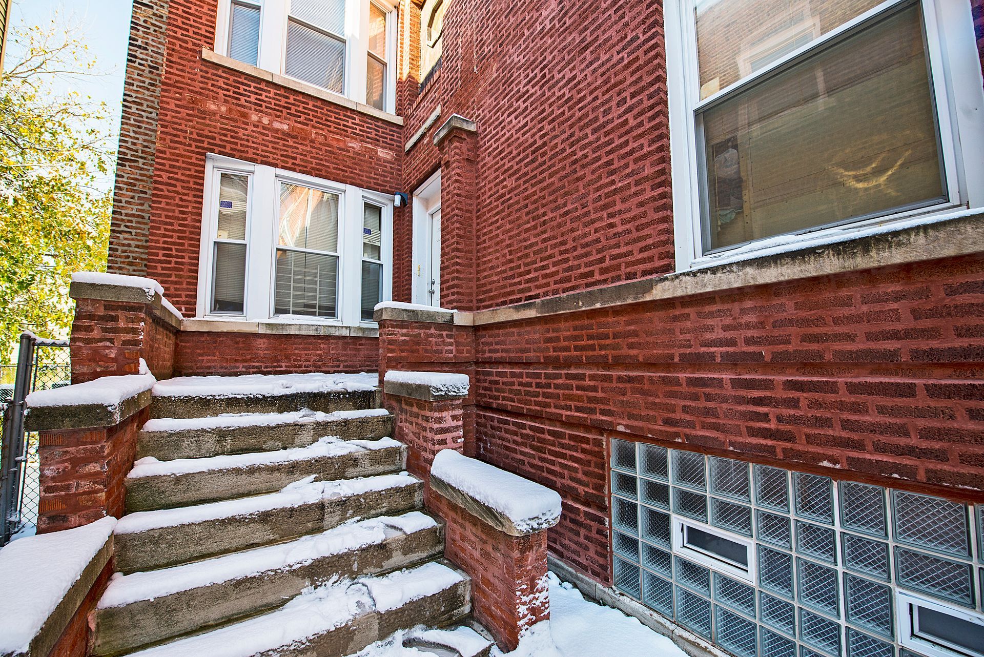 Brick building exterior with snow-covered steps and windows, including a glass block window.