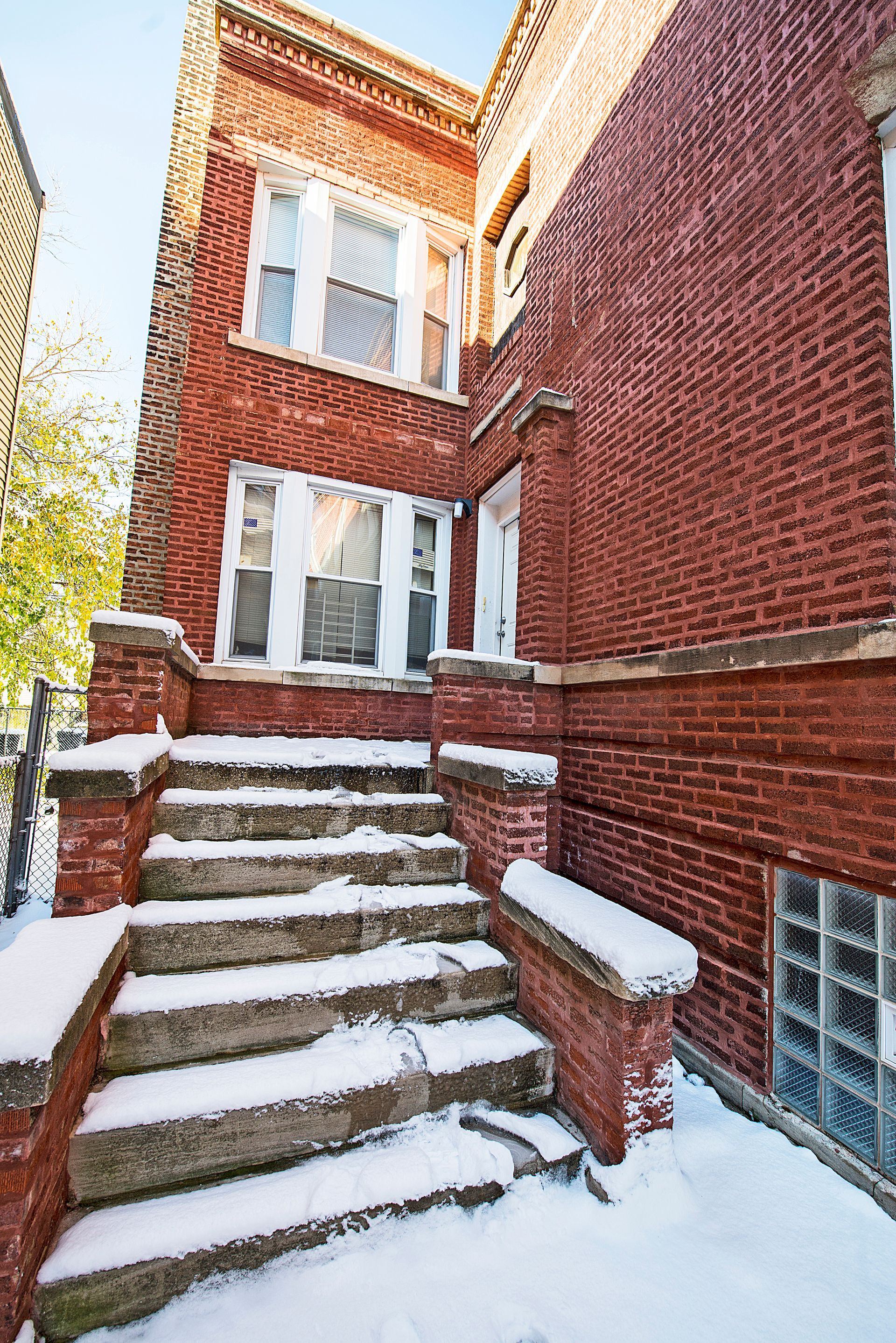 Red brick building with snow-covered steps and a small porch.