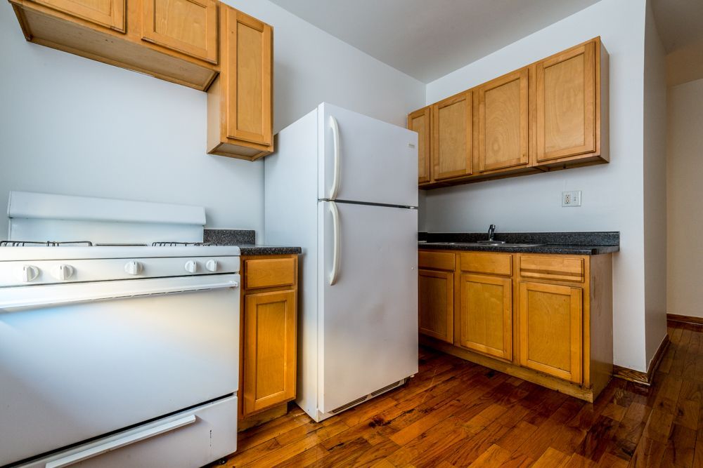 Kitchen with white appliances and wood cabinets on a wood floor.
