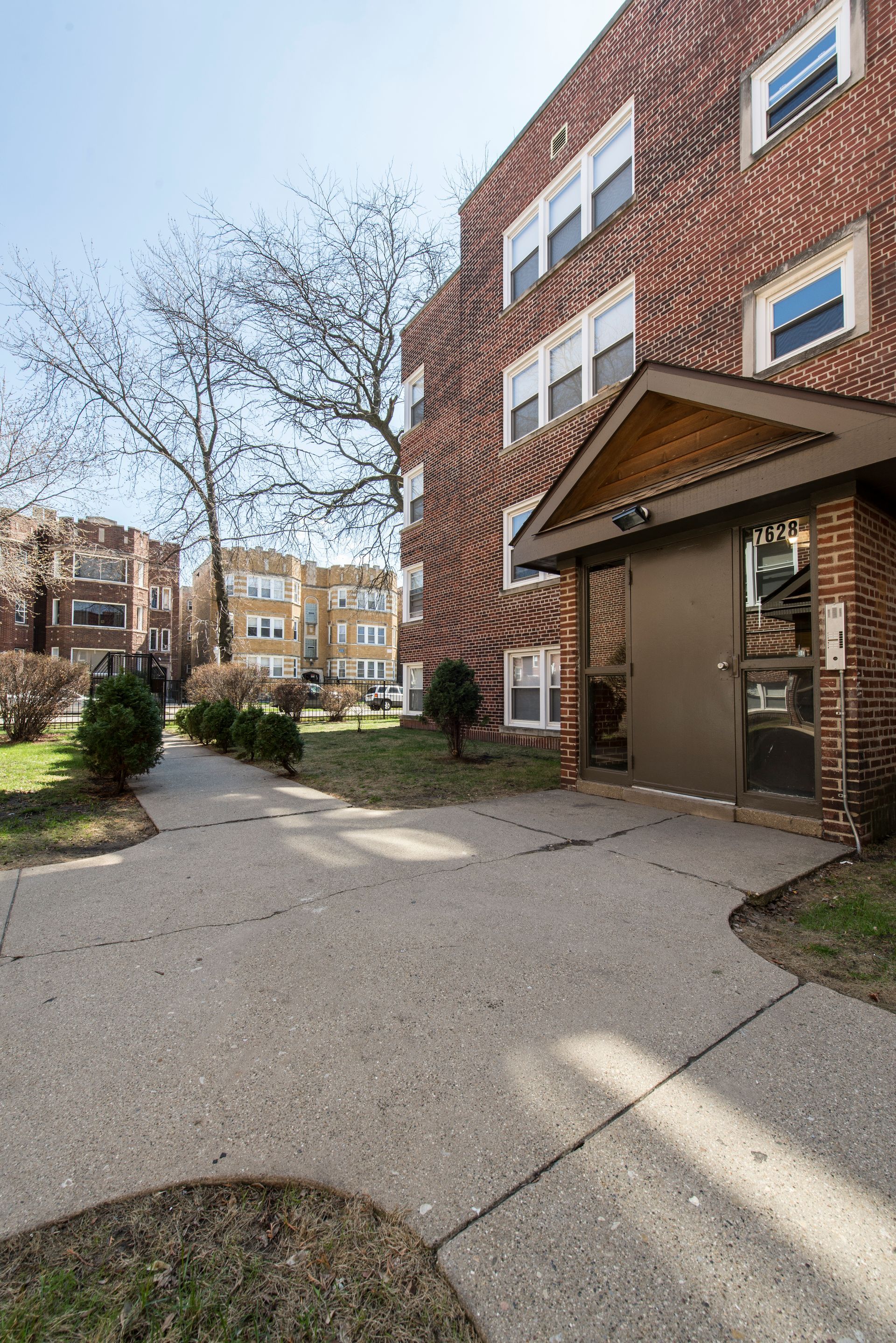 Brick apartment building with concrete pathway leading to the entrance.