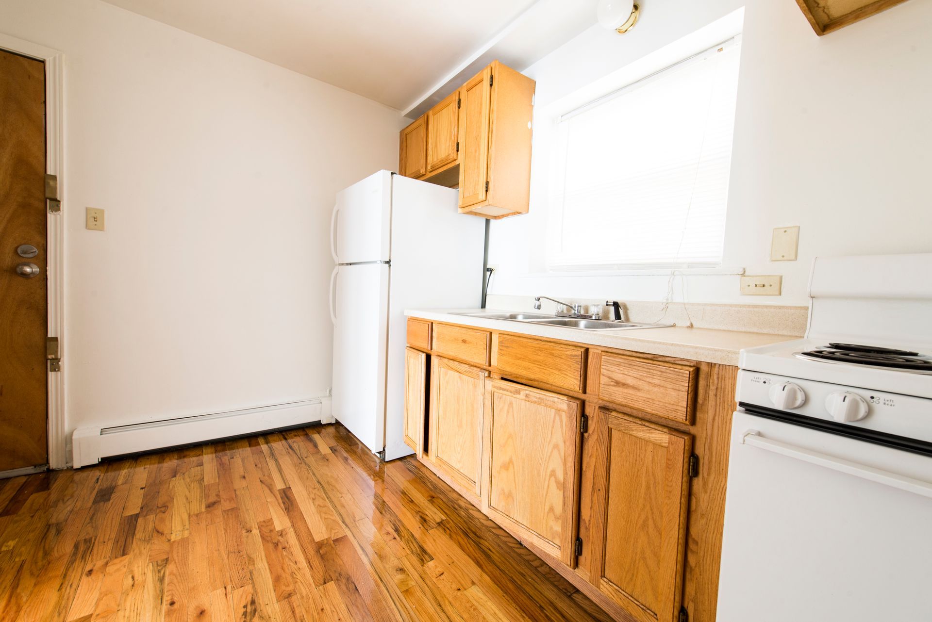 Kitchen with wooden cabinets, white appliances, and hardwood floor.