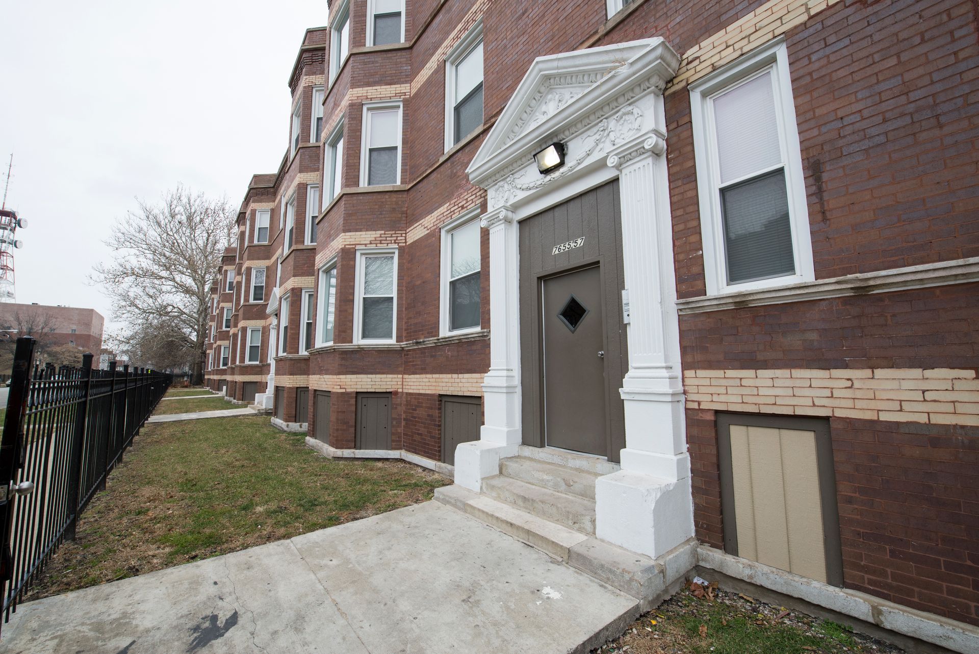 Brick apartment building with white door trim, steps, and windows.