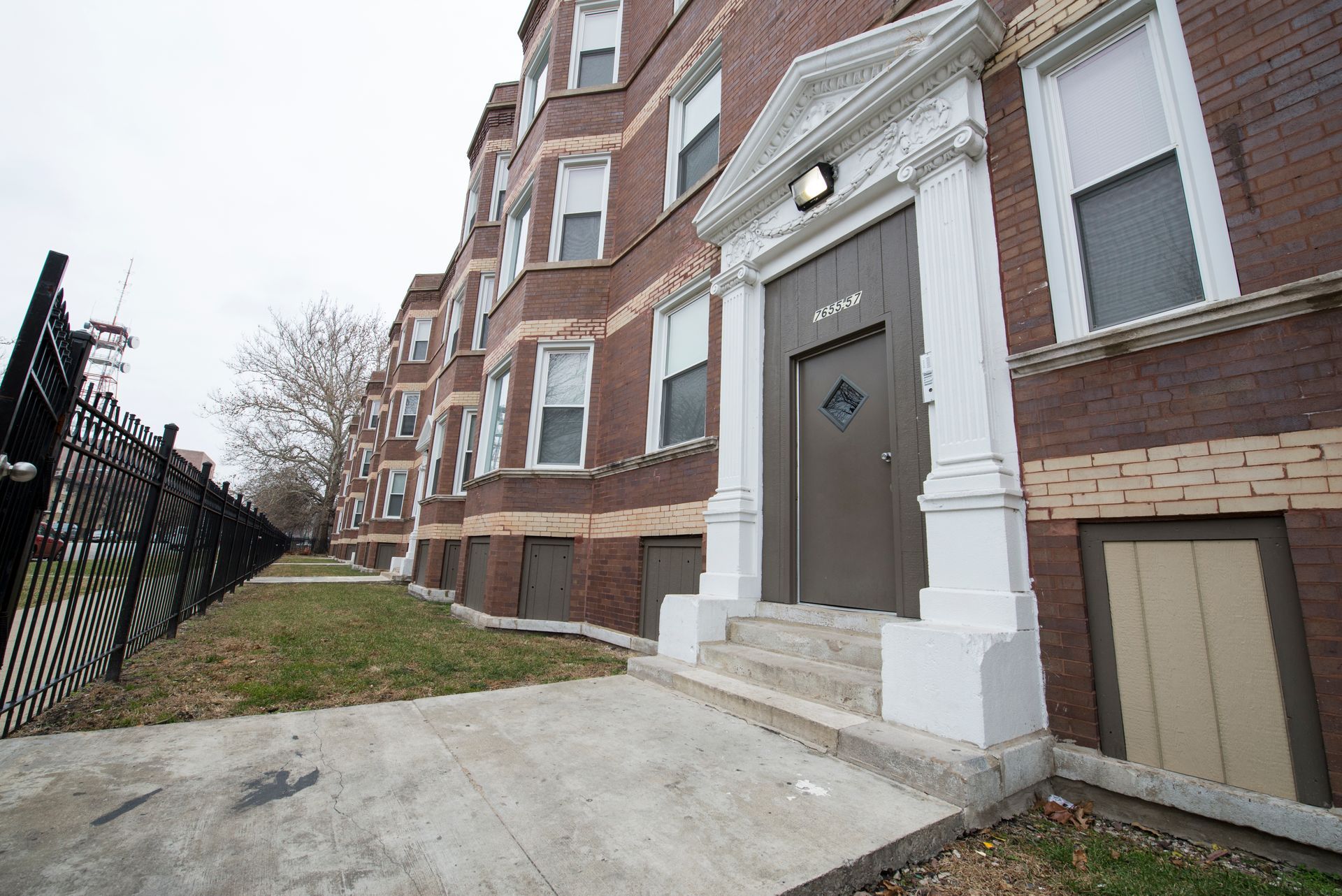 Brown brick apartment building with white trim around windows and door.