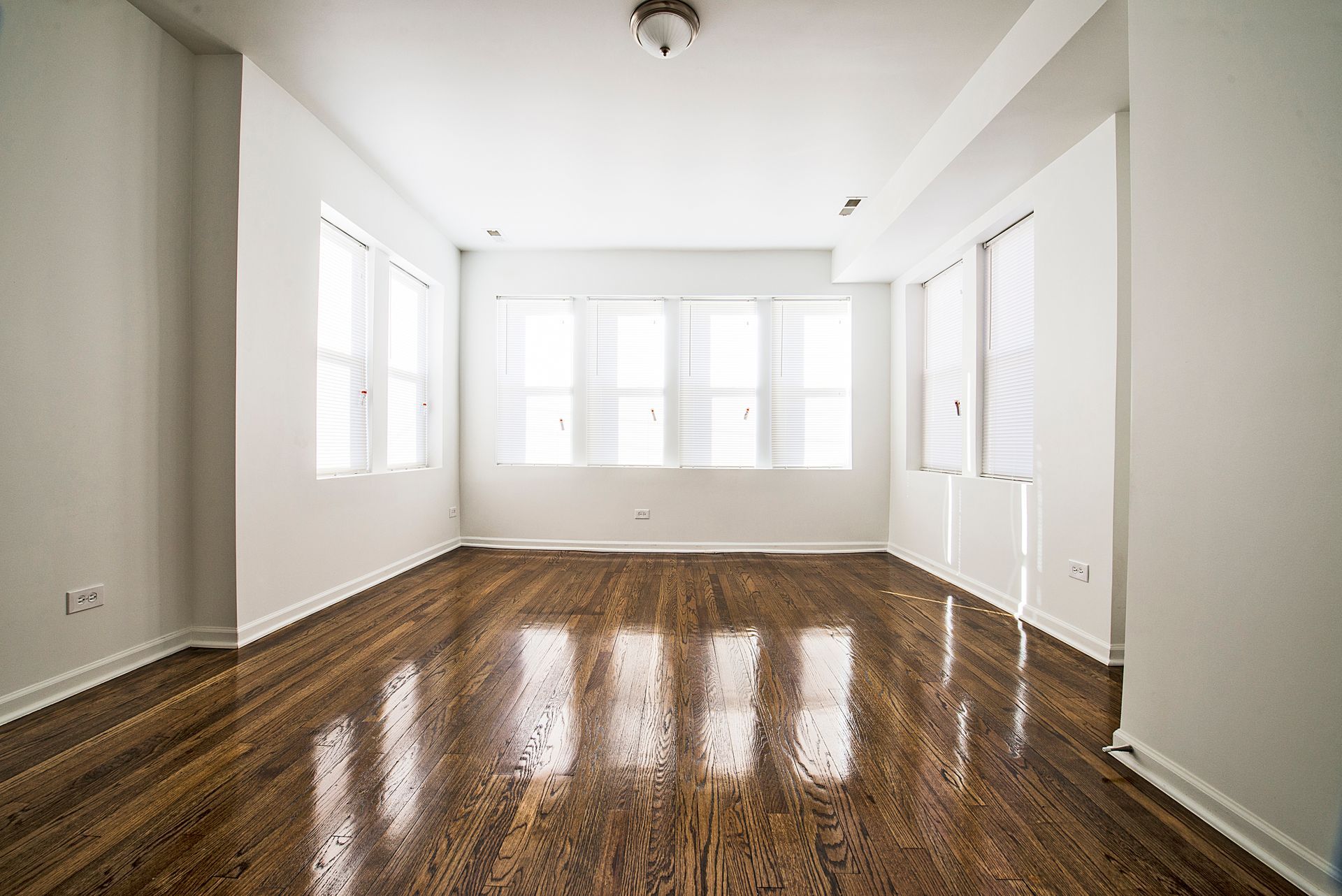 Empty room with wood floor and several windows. White walls and ceiling.