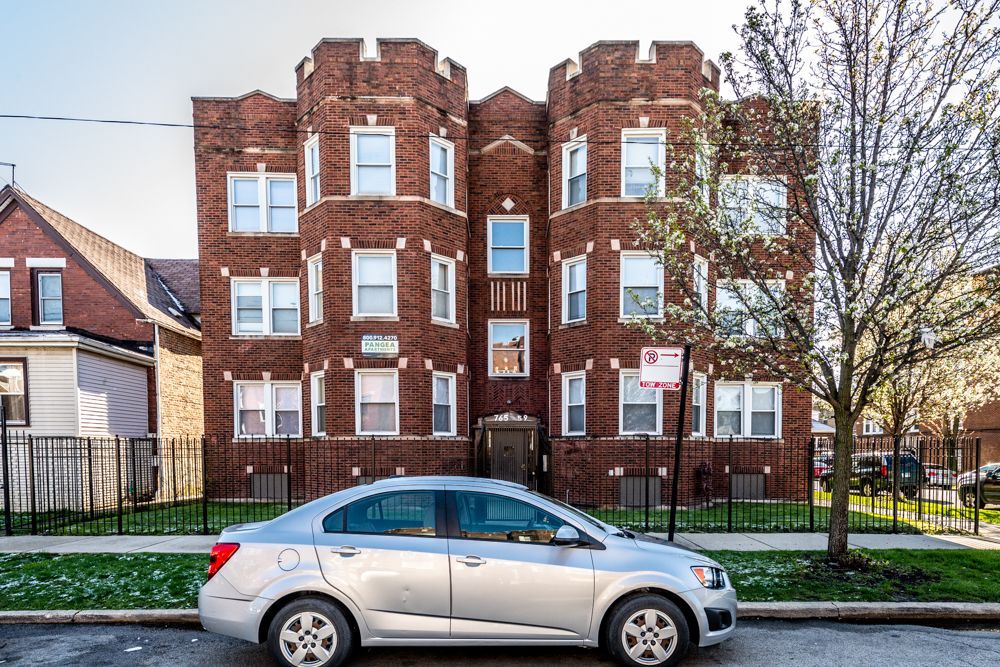 Brick apartment building with turrets, parked car in front.