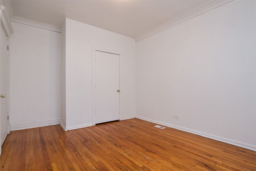 Empty room with hardwood floors, white walls, and a closed door.