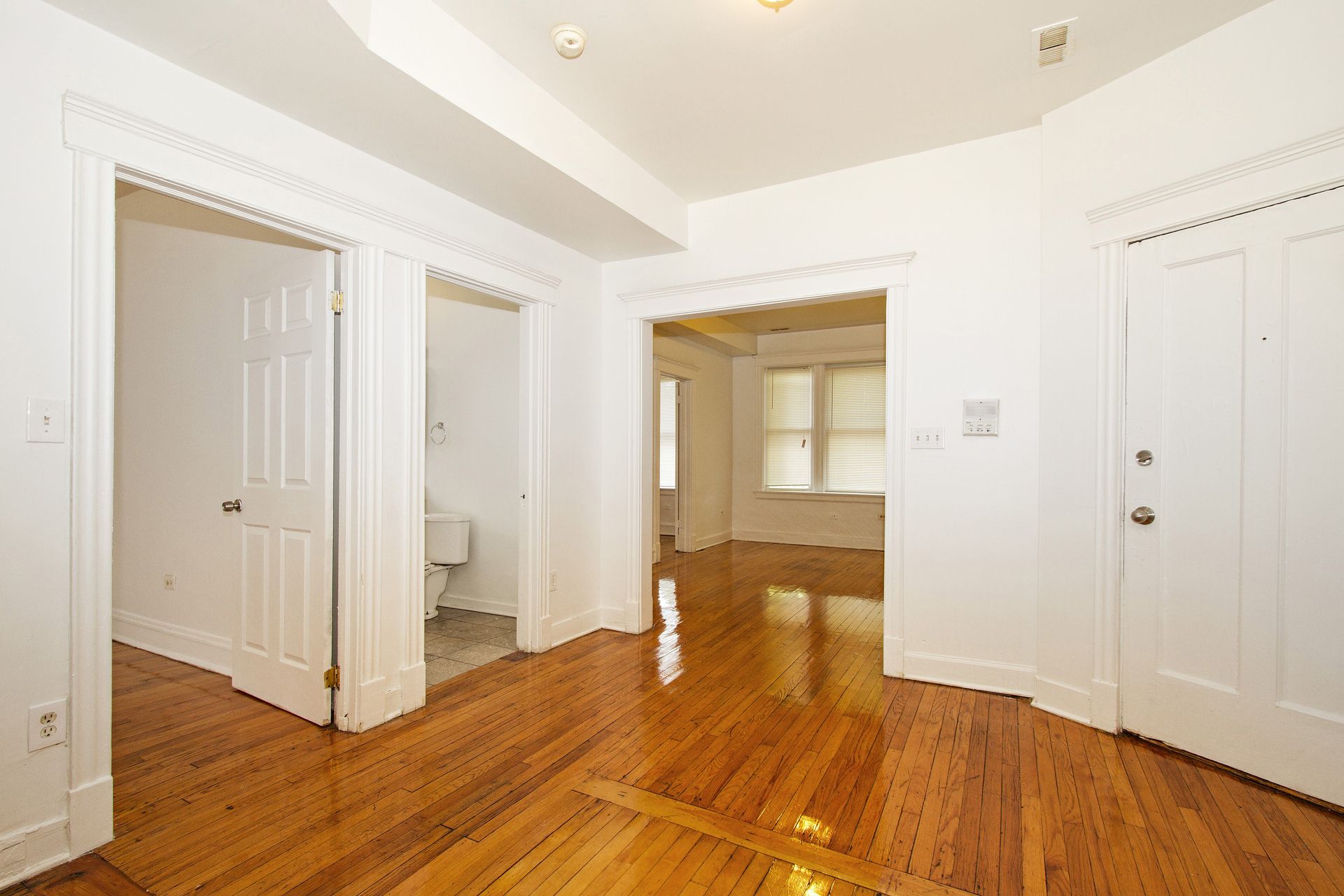 Interior room with hardwood floors, white doors, and doorways leading to other rooms.