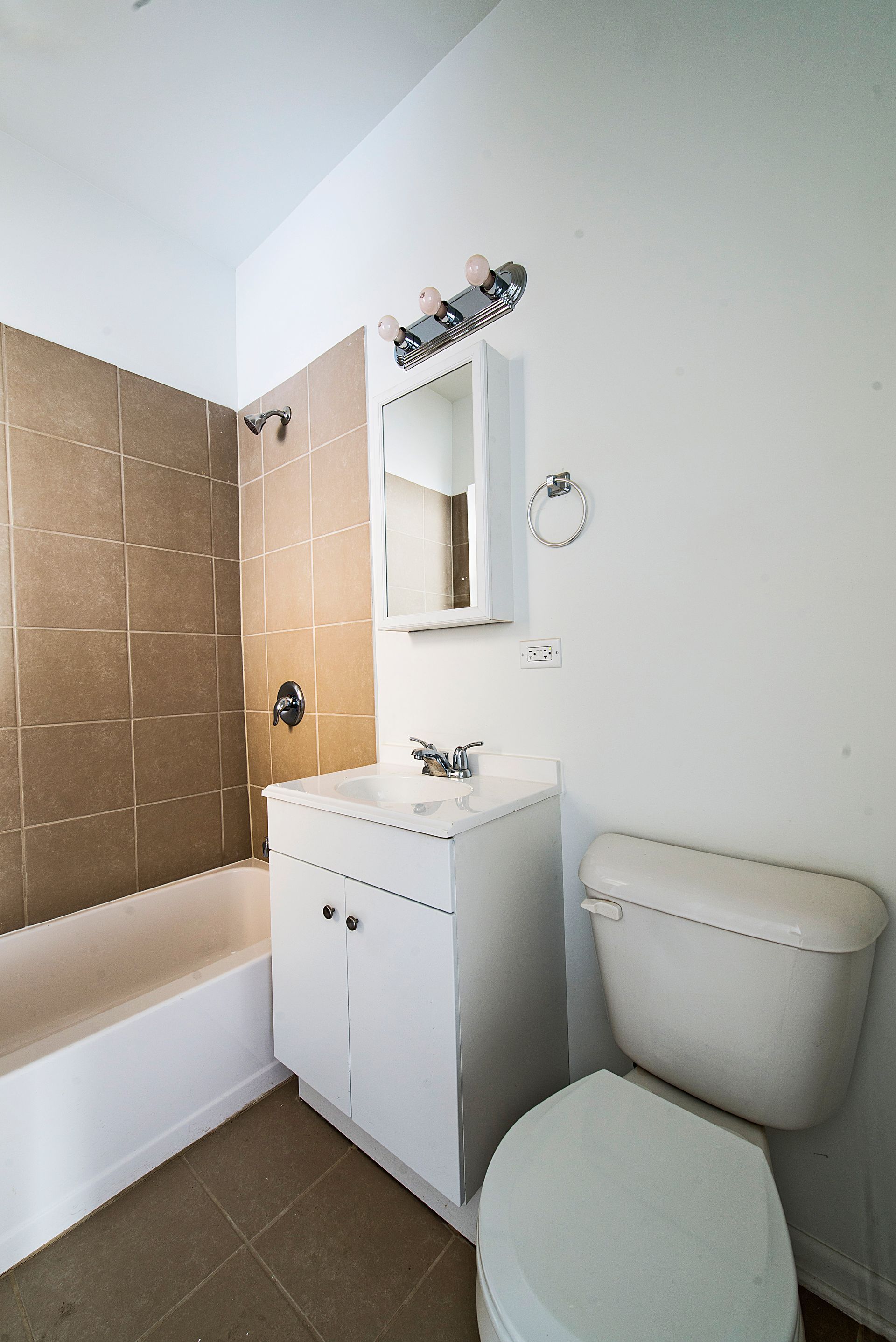 Bathroom with white fixtures, tan tile, and a medicine cabinet above a sink.
