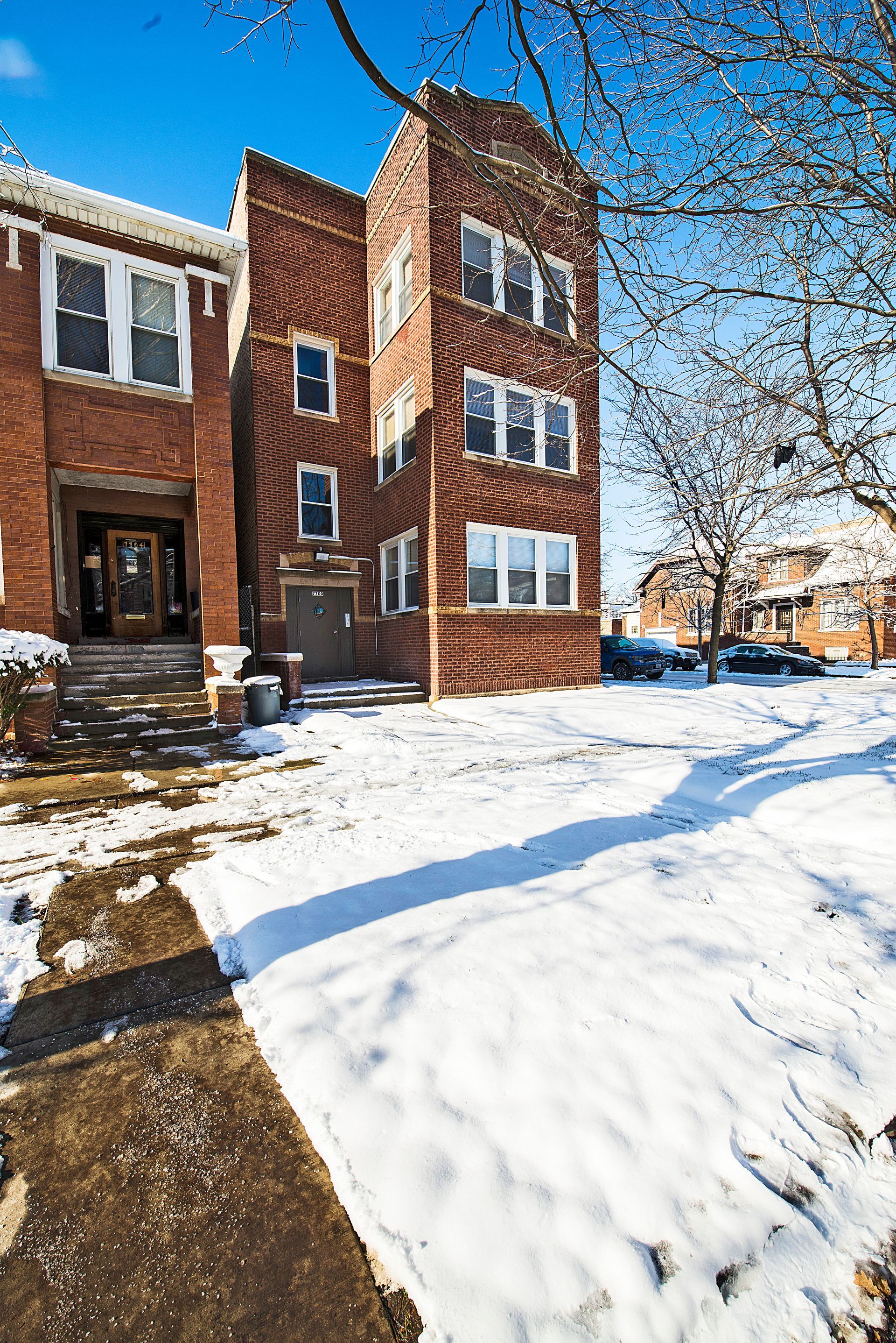 Brick apartment building in winter, snowy yard, sunny day.