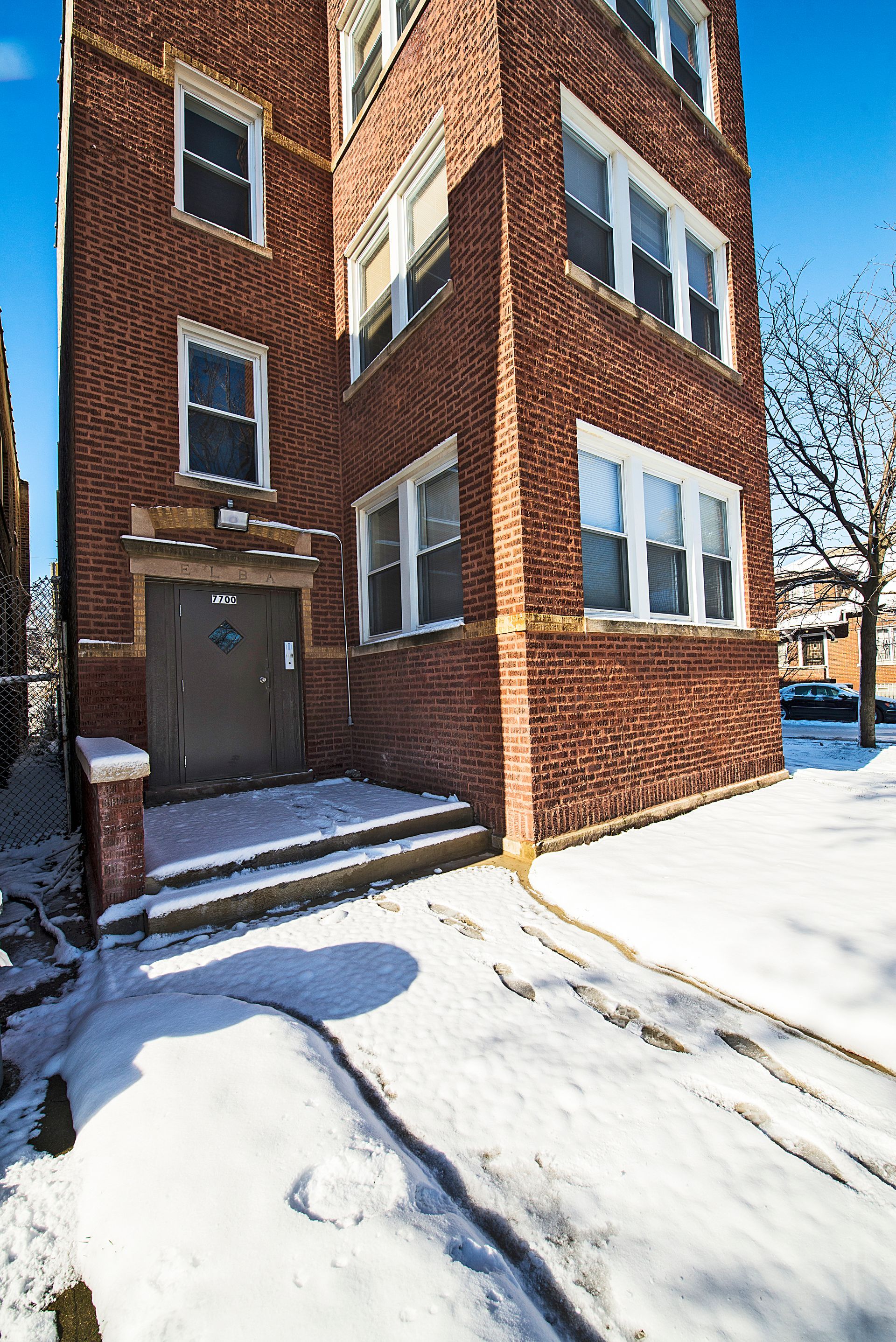 Brick apartment building entrance, snow-covered walkway.