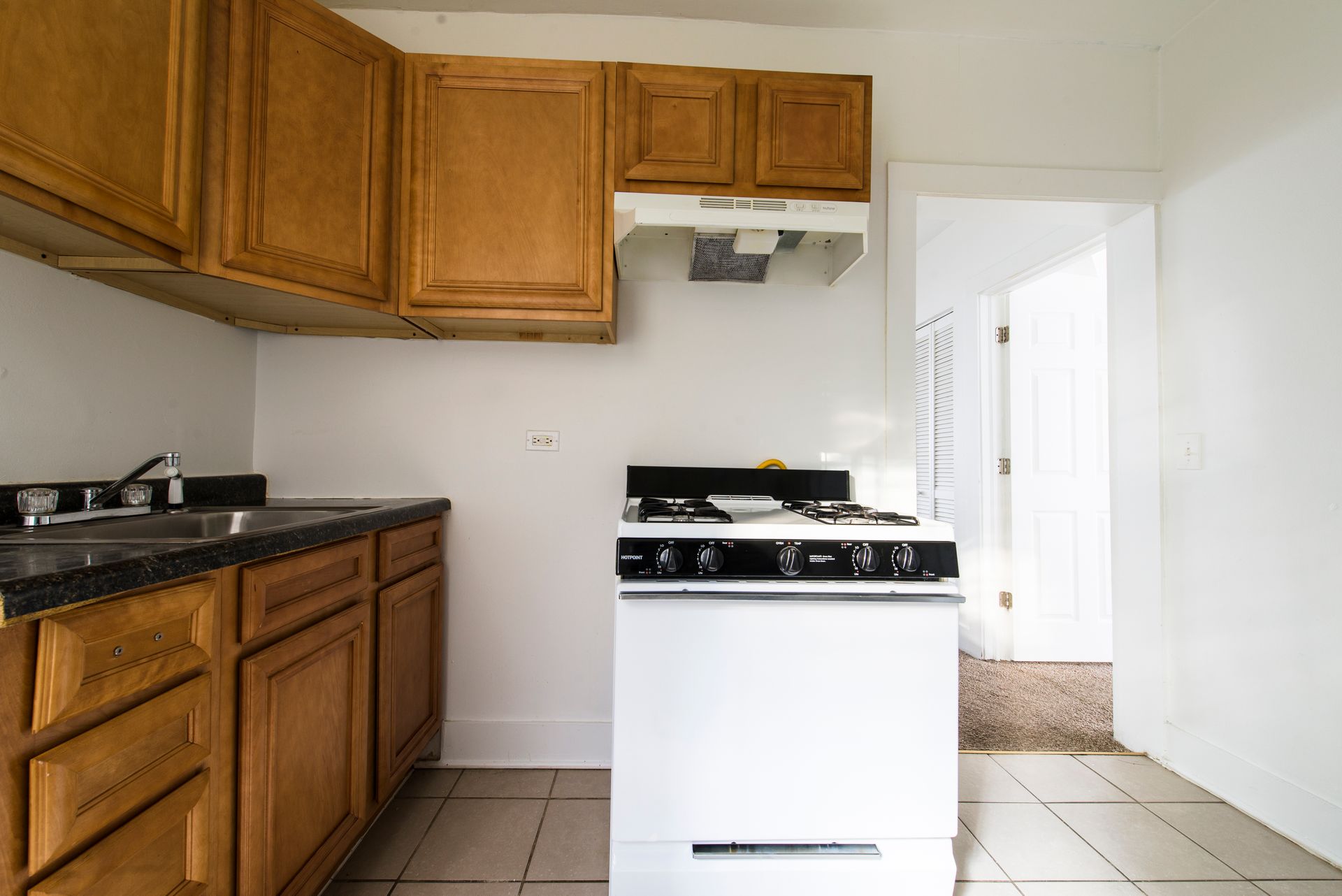 Kitchen with light brown cabinets, white stove, and doorway.