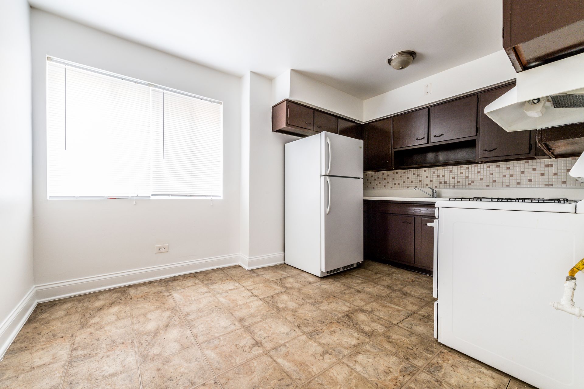 Kitchen with brown cabinets, white appliances, and a window.