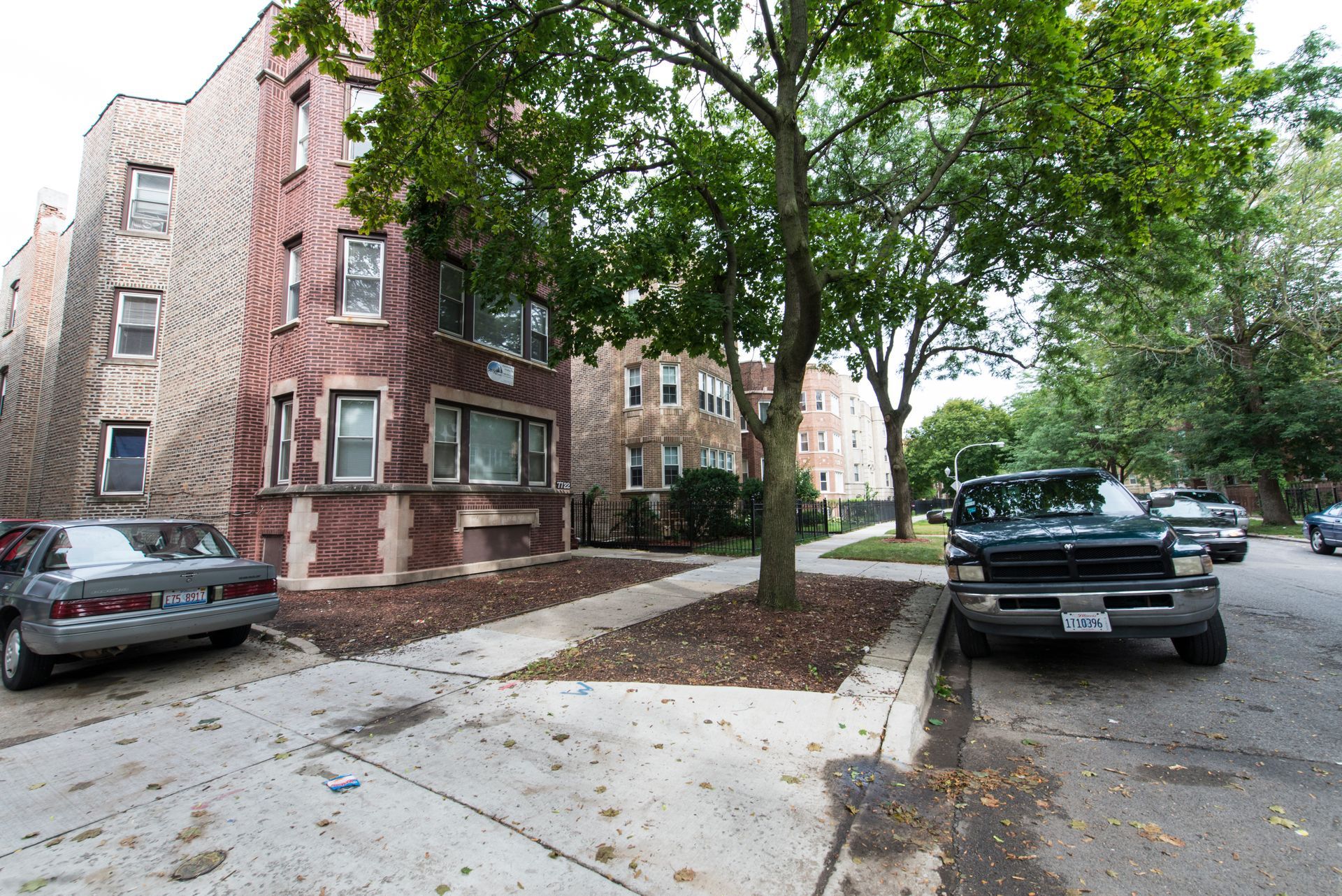 Residential street with parked cars and apartment buildings.