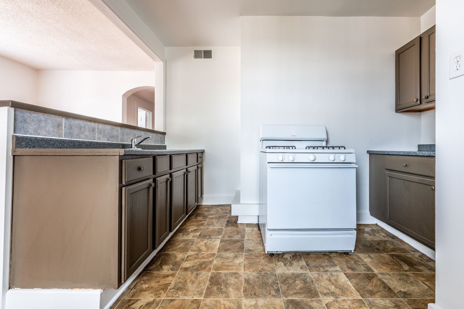 Kitchen with white appliances, brown cabinets, and patterned floor.