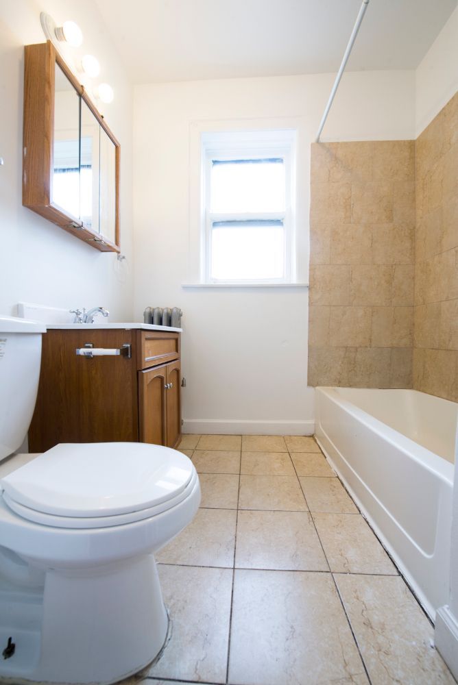 Bathroom with toilet, vanity, window, and tiled shower/tub.