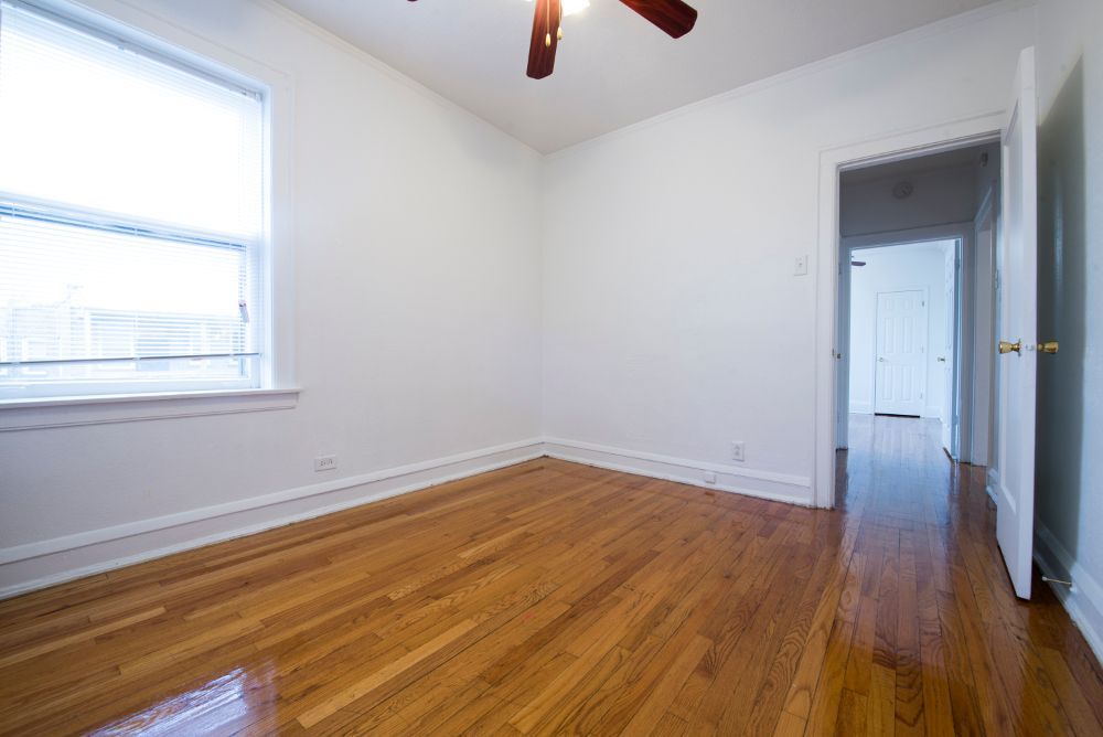 Empty room with wood floors, white walls, and an open doorway.