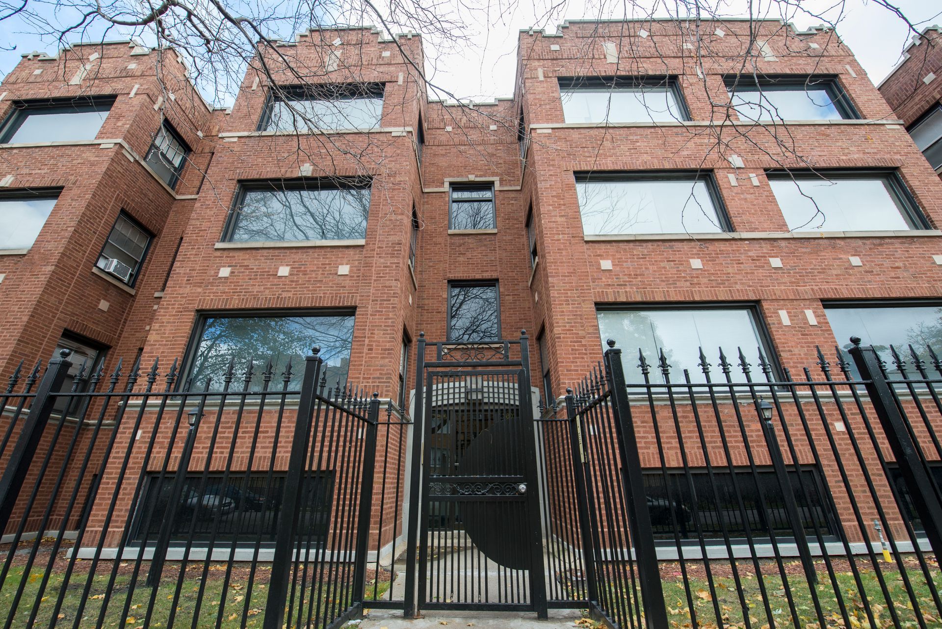 Brick apartment building behind a black iron fence.