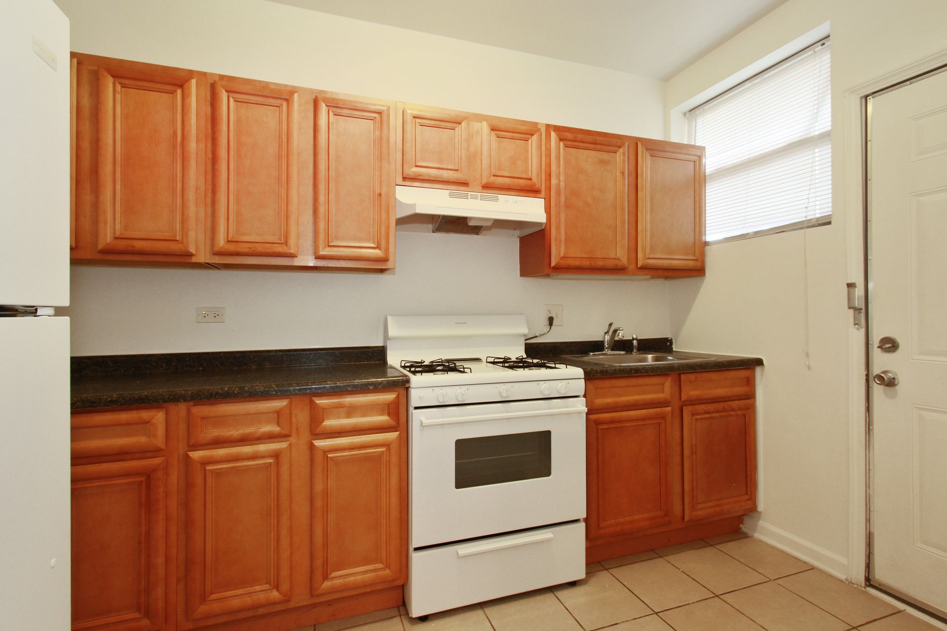 Kitchen with wooden cabinets, white stove, and door.