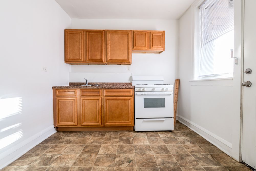 Small kitchen with brown cabinets, white stove, and window.