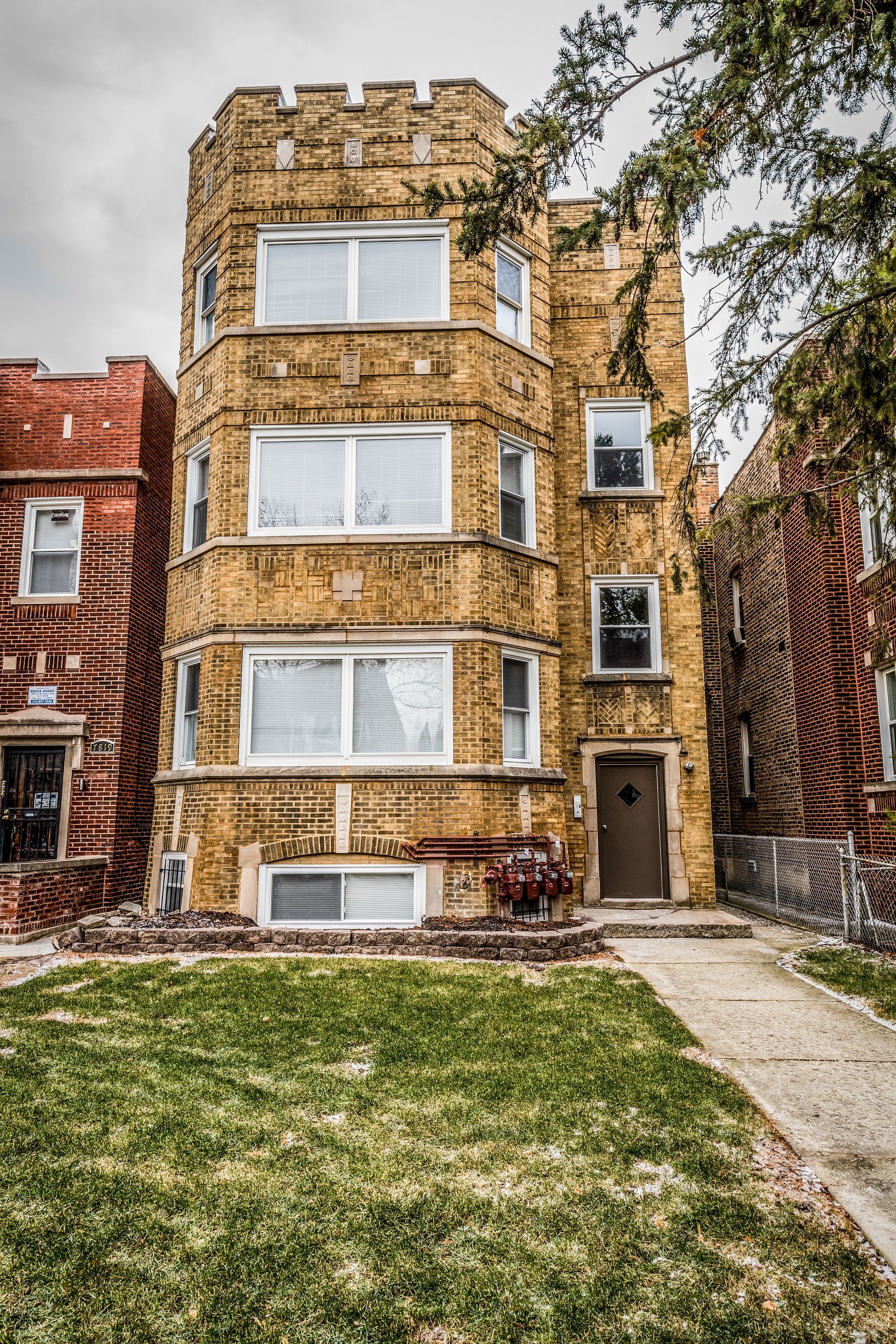 Multi-story brick building with rounded facade. Brown, cream and red brick. Windows on multiple levels.