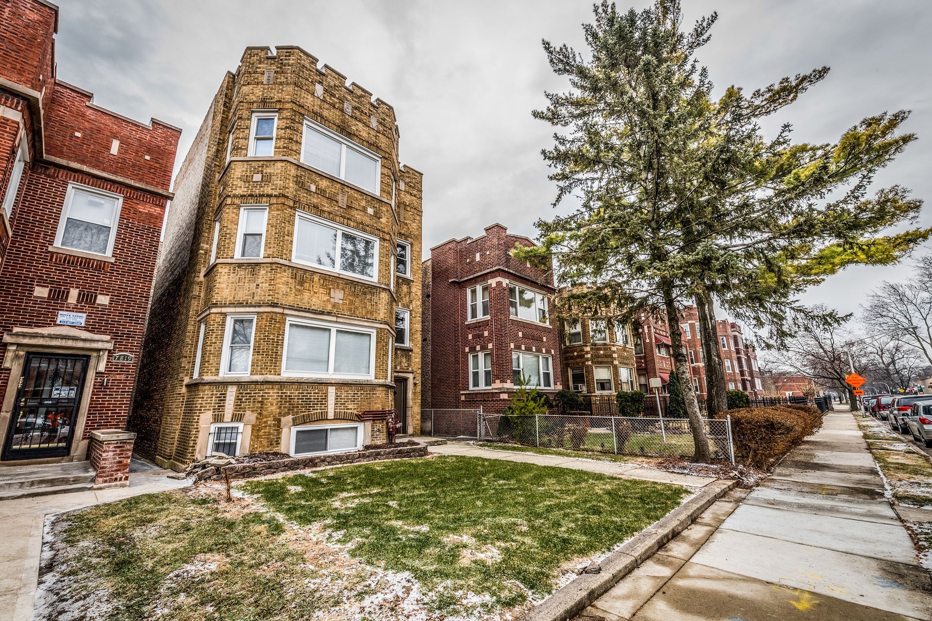 Three-story brick apartment buildings with a small front yard and sidewalk.