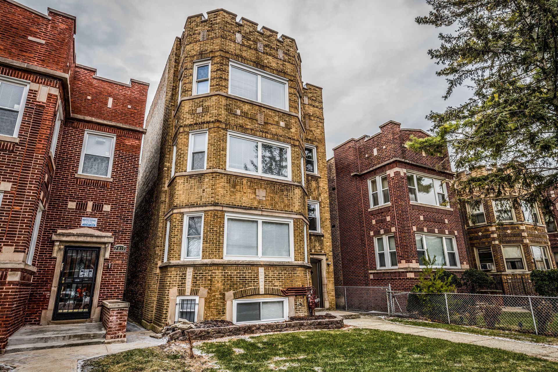 Brick apartment buildings on a cloudy day; green lawn in front of the middle building.
