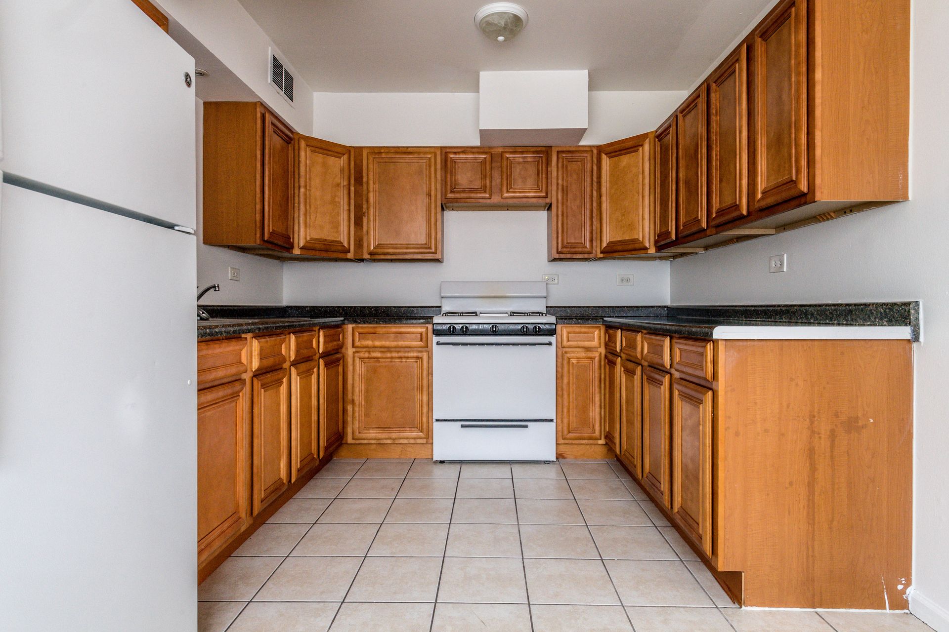 Kitchen with light brown cabinets, white appliances, and gray countertops.