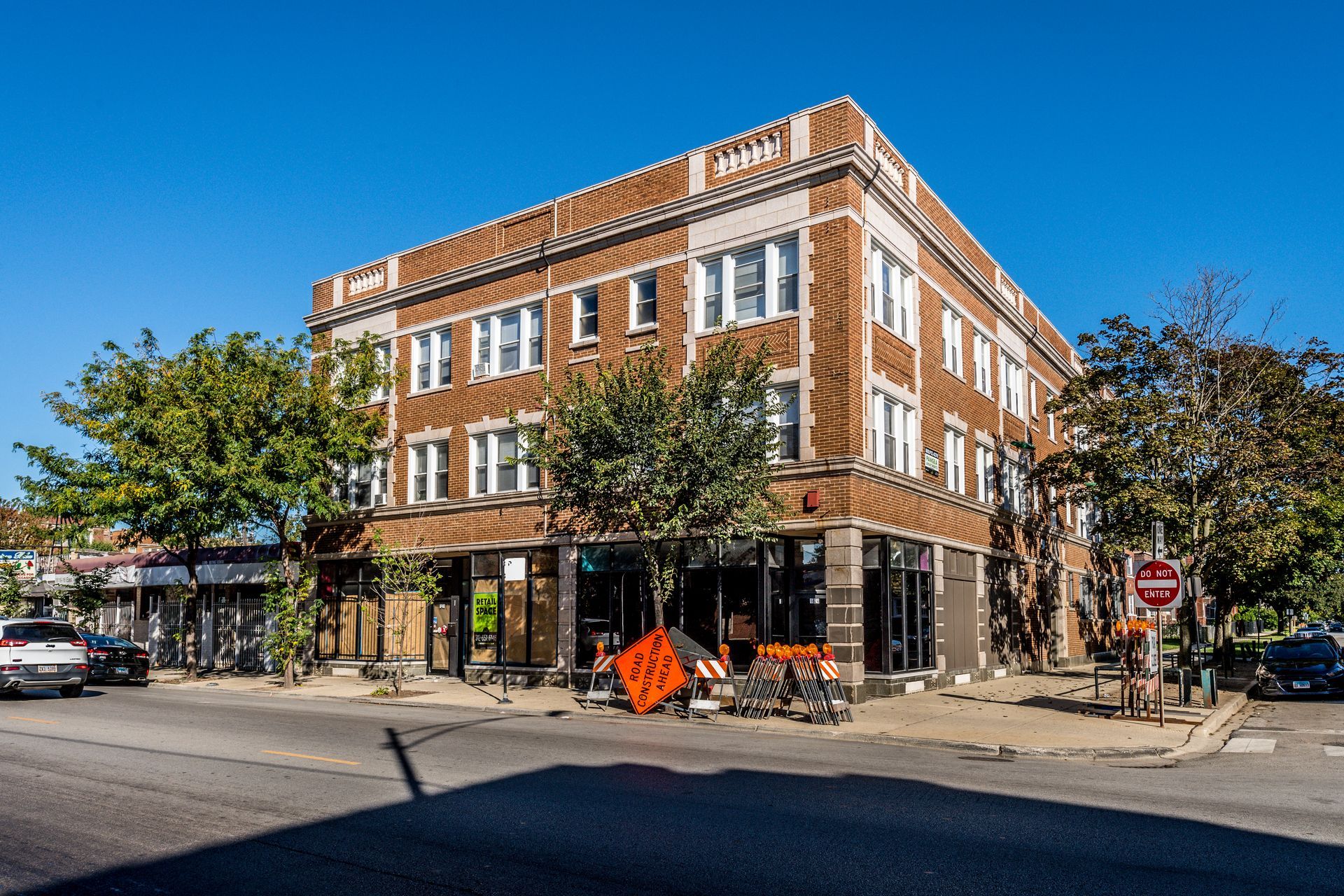 Three-story brick building on a corner lot; road closed sign in front.