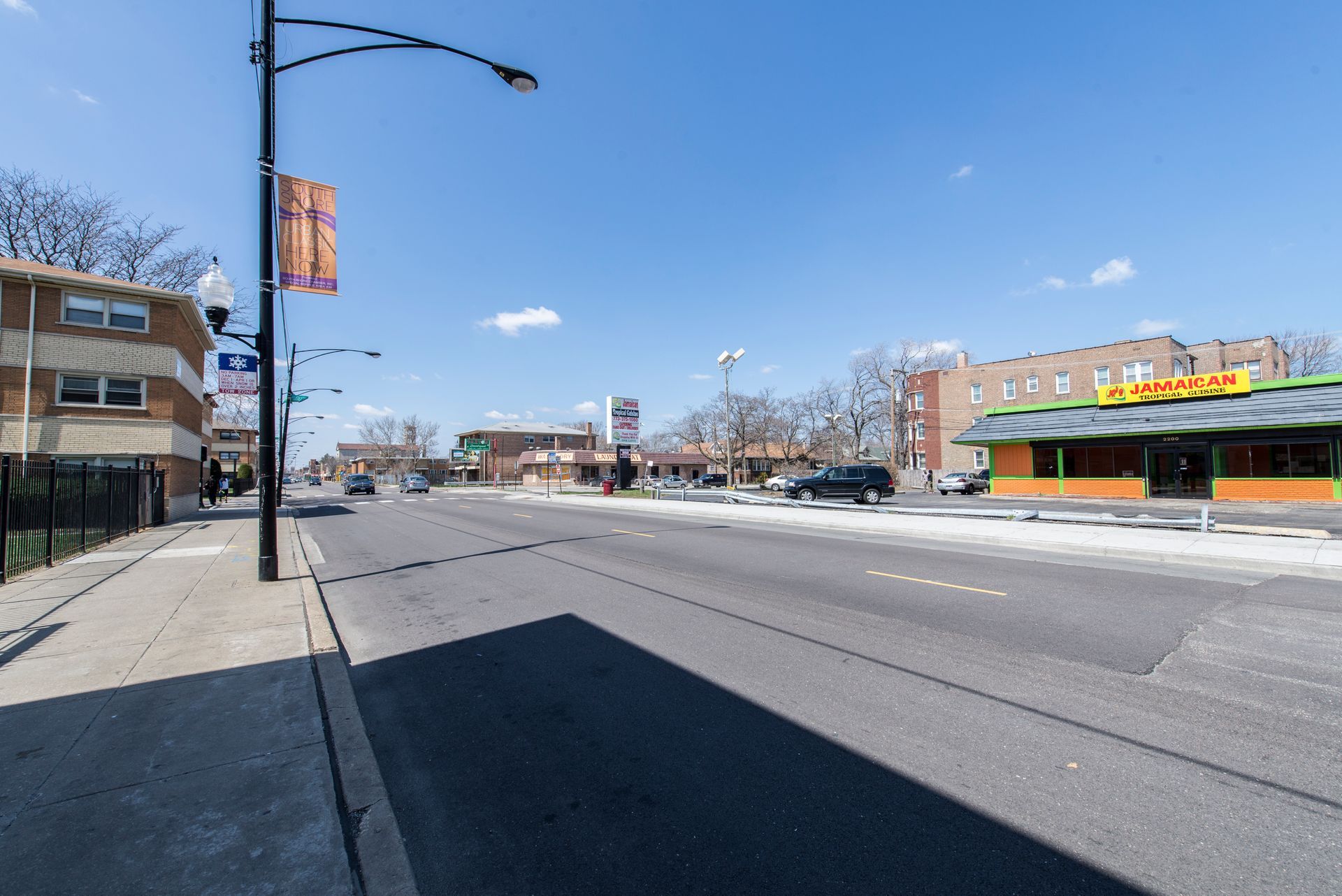Street view with businesses, cars, and a clear blue sky.