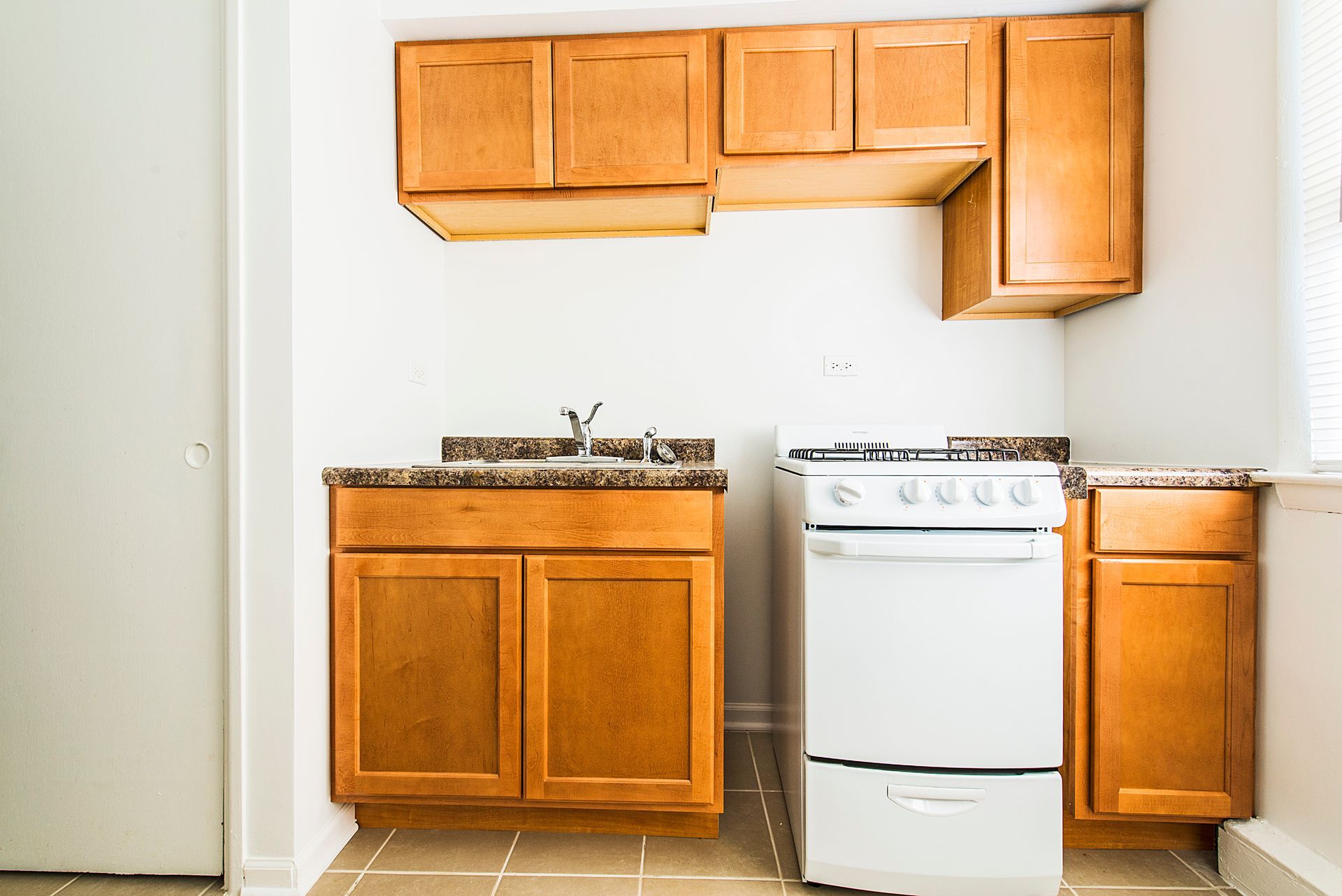 Small kitchen with wood cabinets, white stove, and sink.