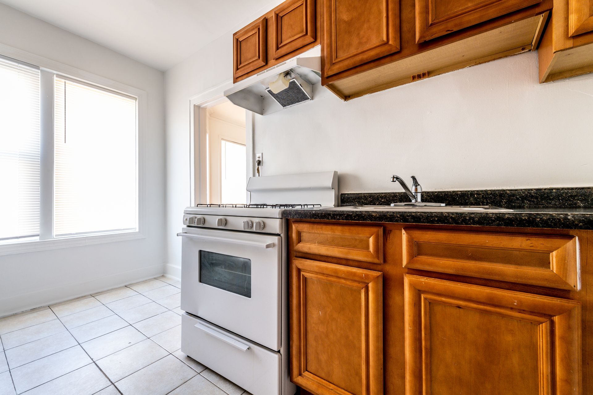 Kitchen with white stove, brown cabinets, and a window.