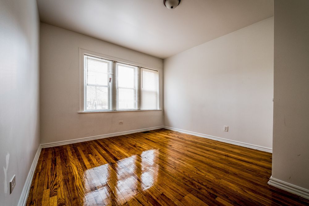 Empty room with hardwood floors and a window. White walls, natural light.