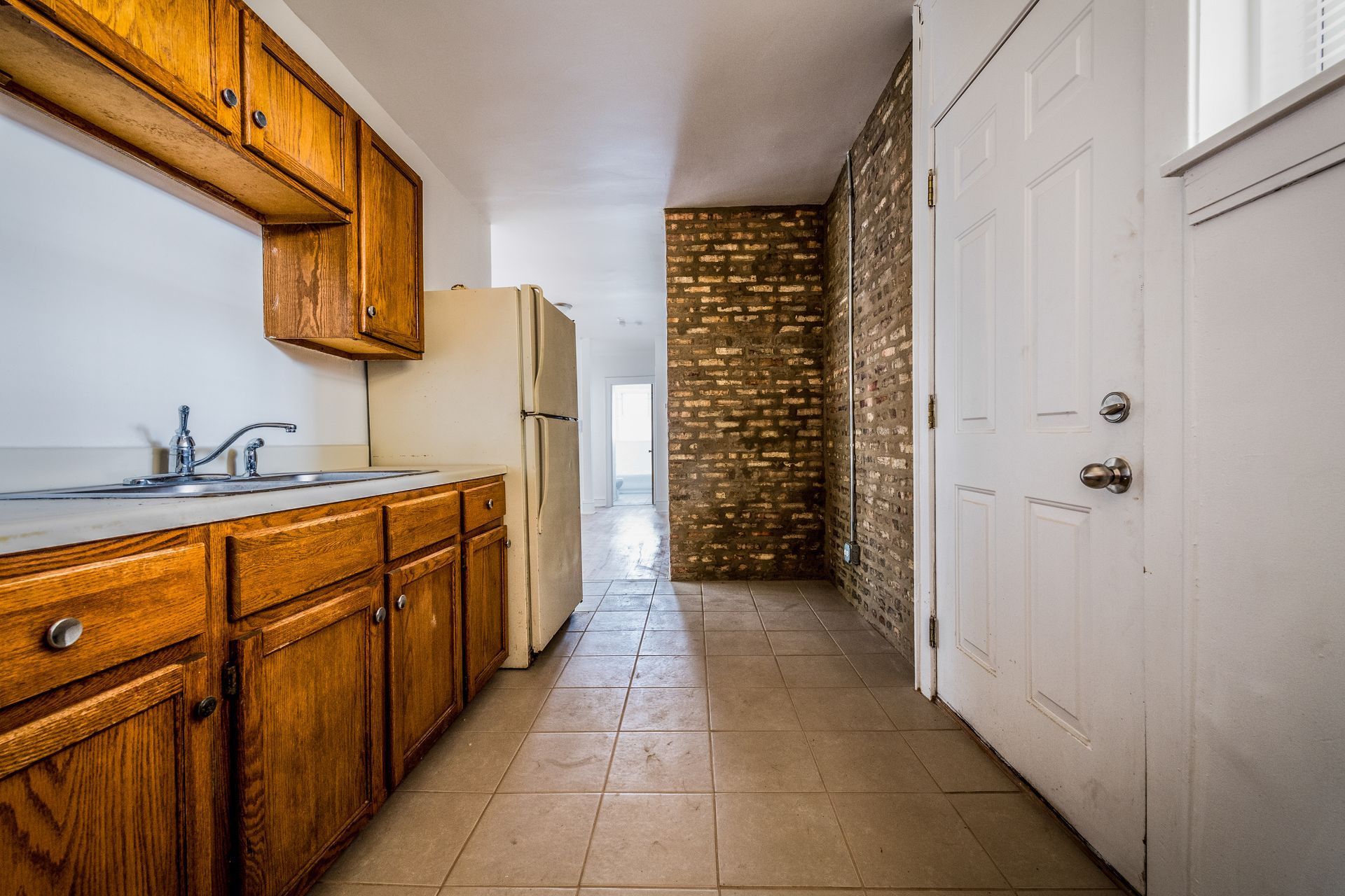 Small kitchen with wood cabinets, white appliances, and tiled floor.