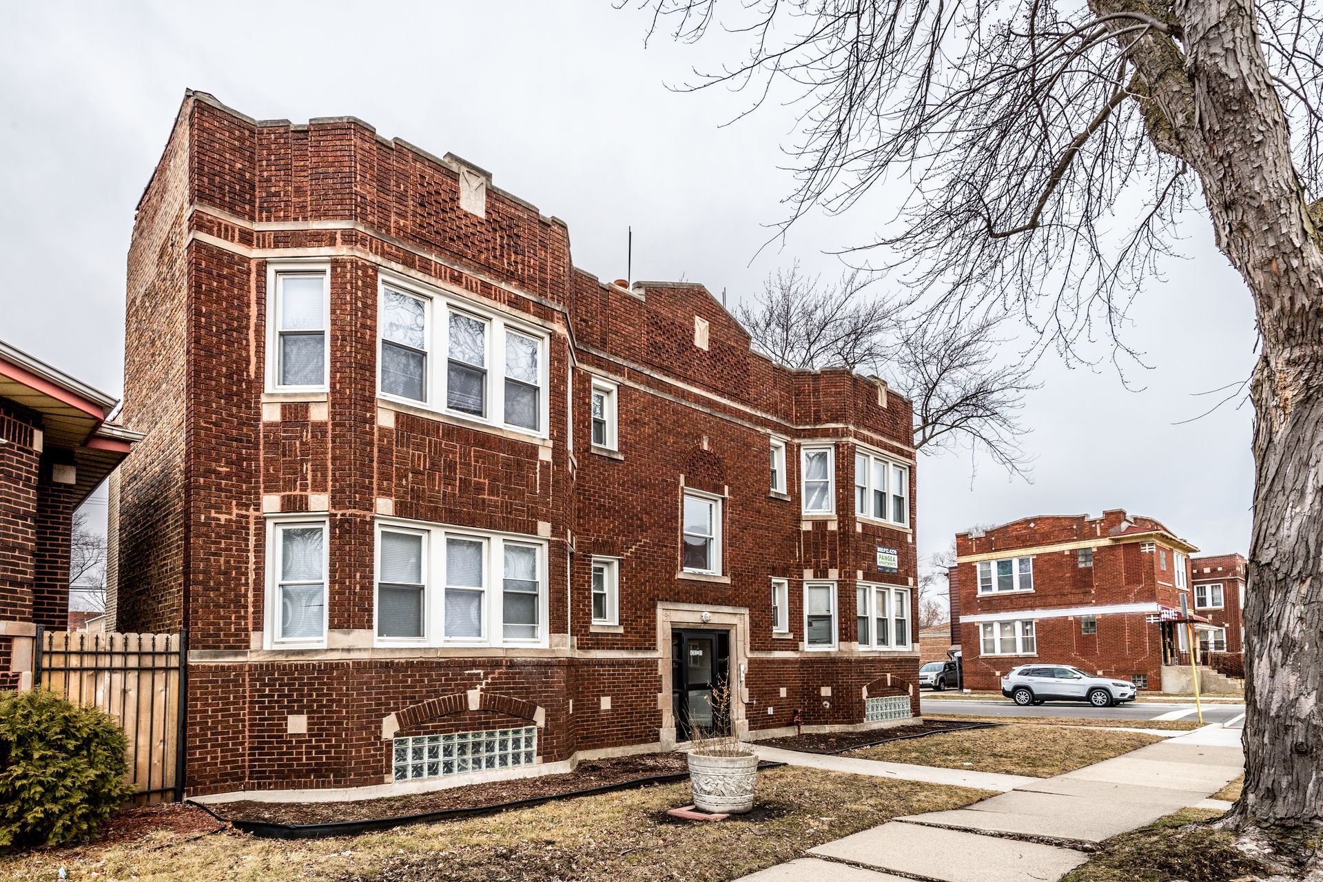 Brick apartment building with white-framed windows, cloudy sky.
