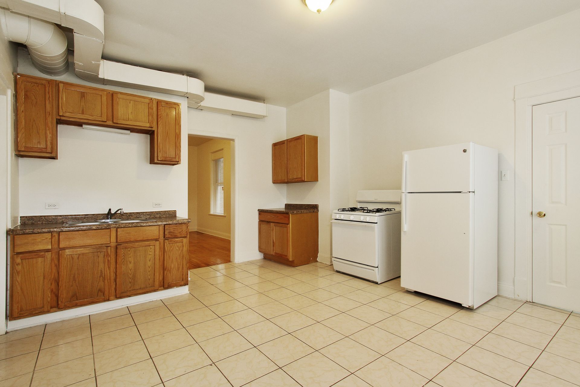 Kitchen with brown cabinets, white appliances, and tiled floor.