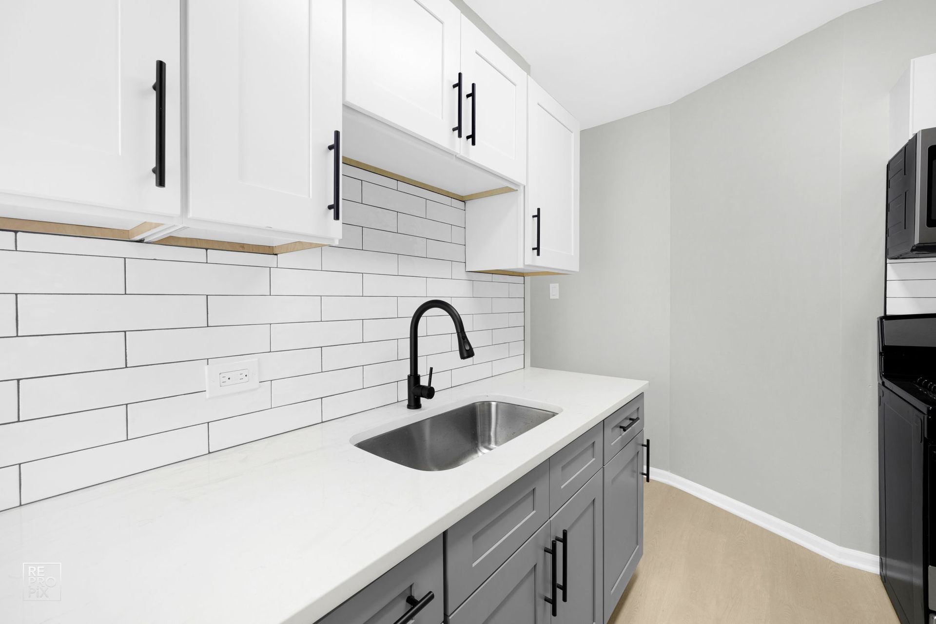Modern kitchen with white upper cabinets, gray lower cabinets, and a white subway tile backsplash.