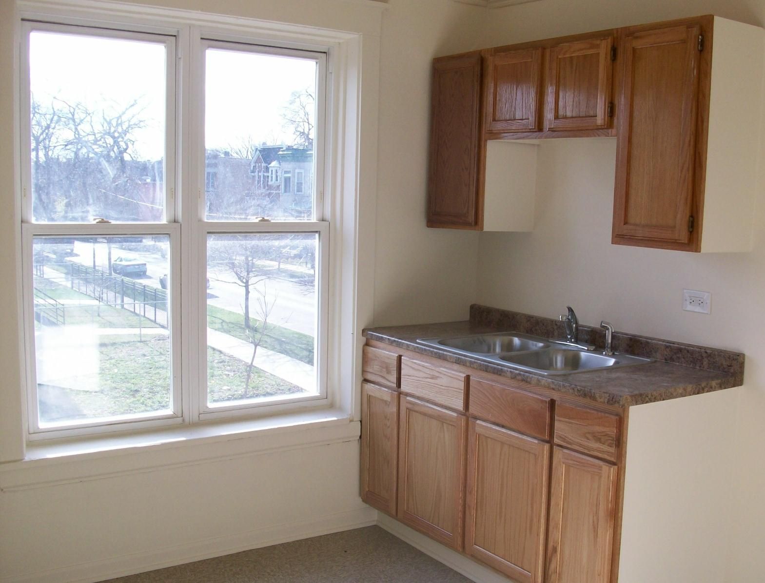 Kitchen with window, wooden cabinets, and countertop with a sink.