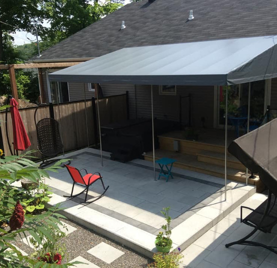 Une cour arrière avec une chaise berçante sous un auvent