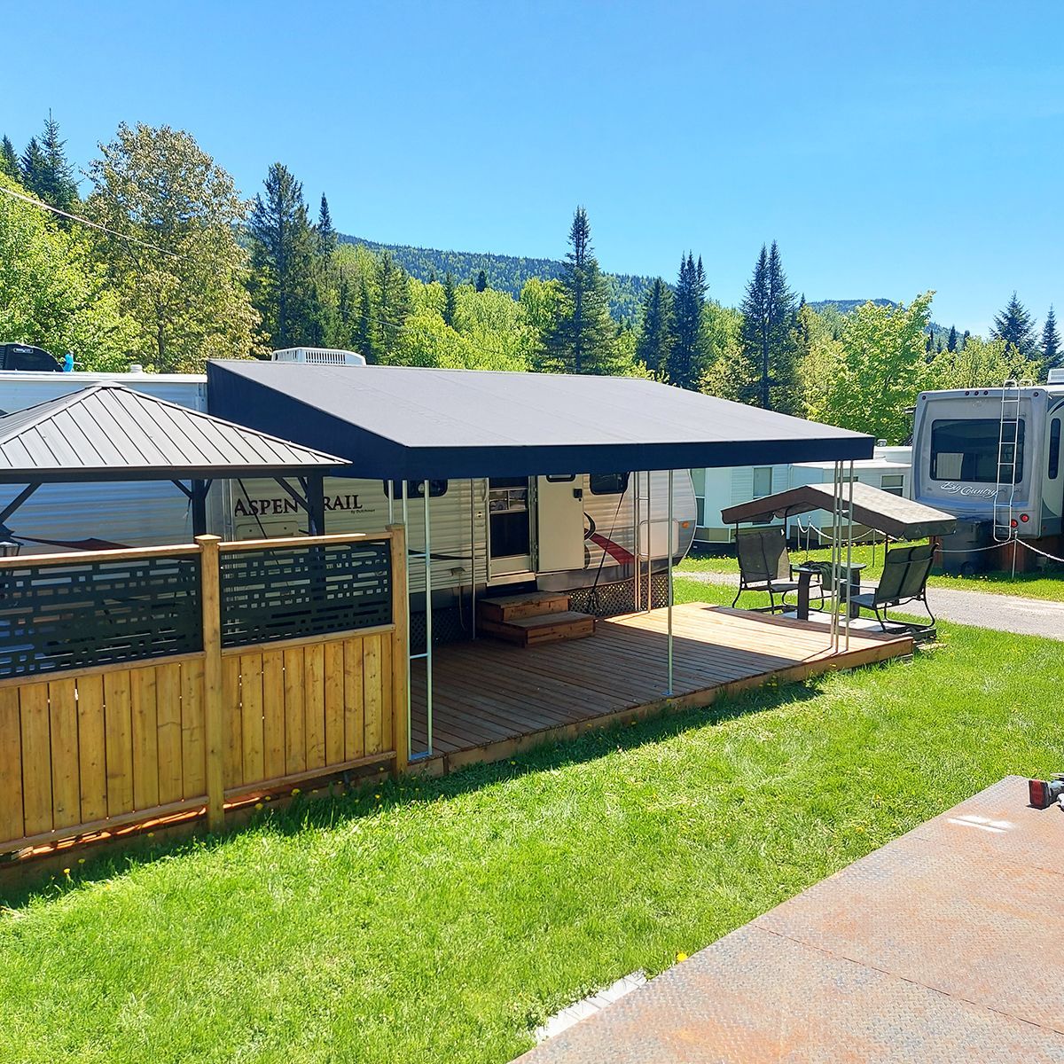 Un camping-car garé dans une zone herbeuse avec un auvent au-dessus.