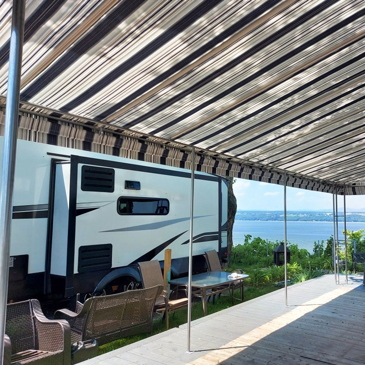 Un camping-car est garé sous un auvent surplombant un lac.