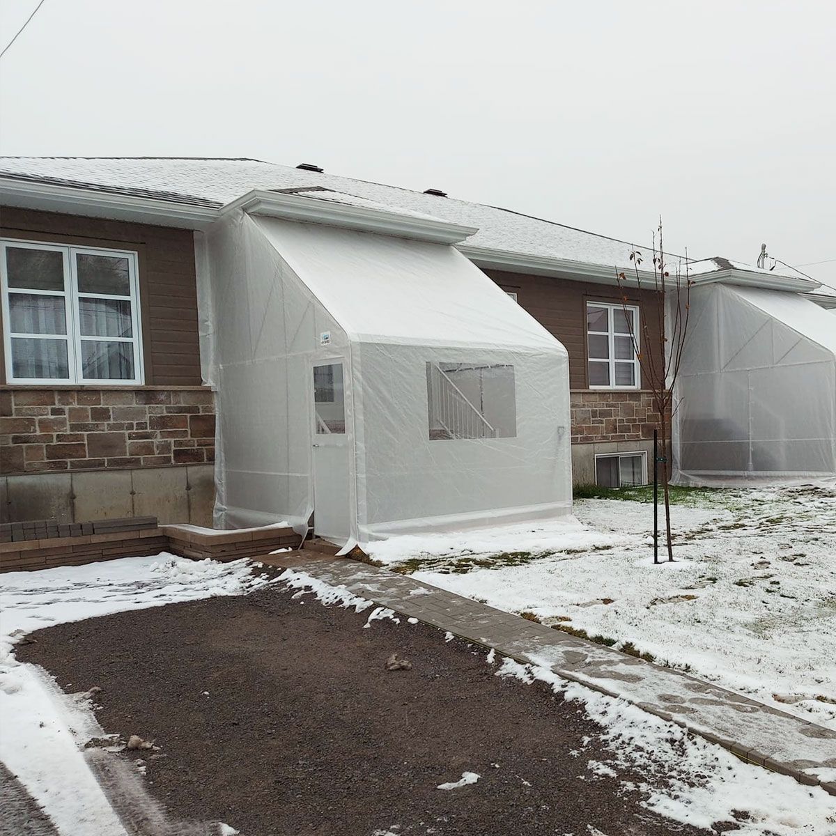 Une maison avec une tente devant dans la neige