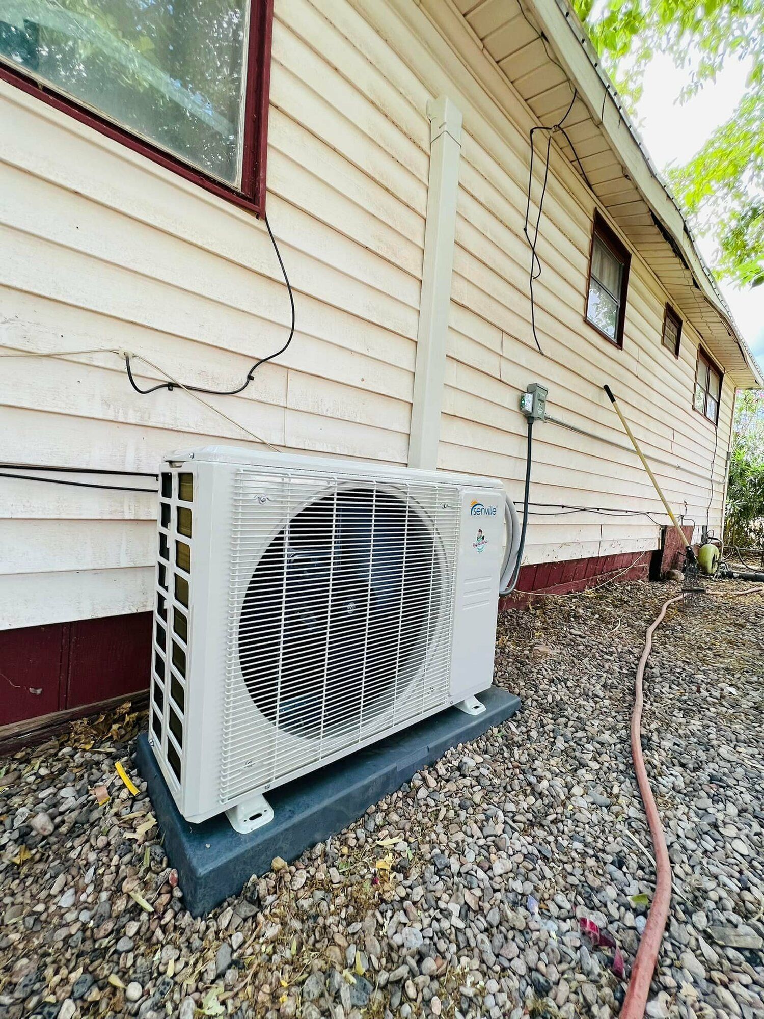 A white air conditioner is sitting on the side of a house.